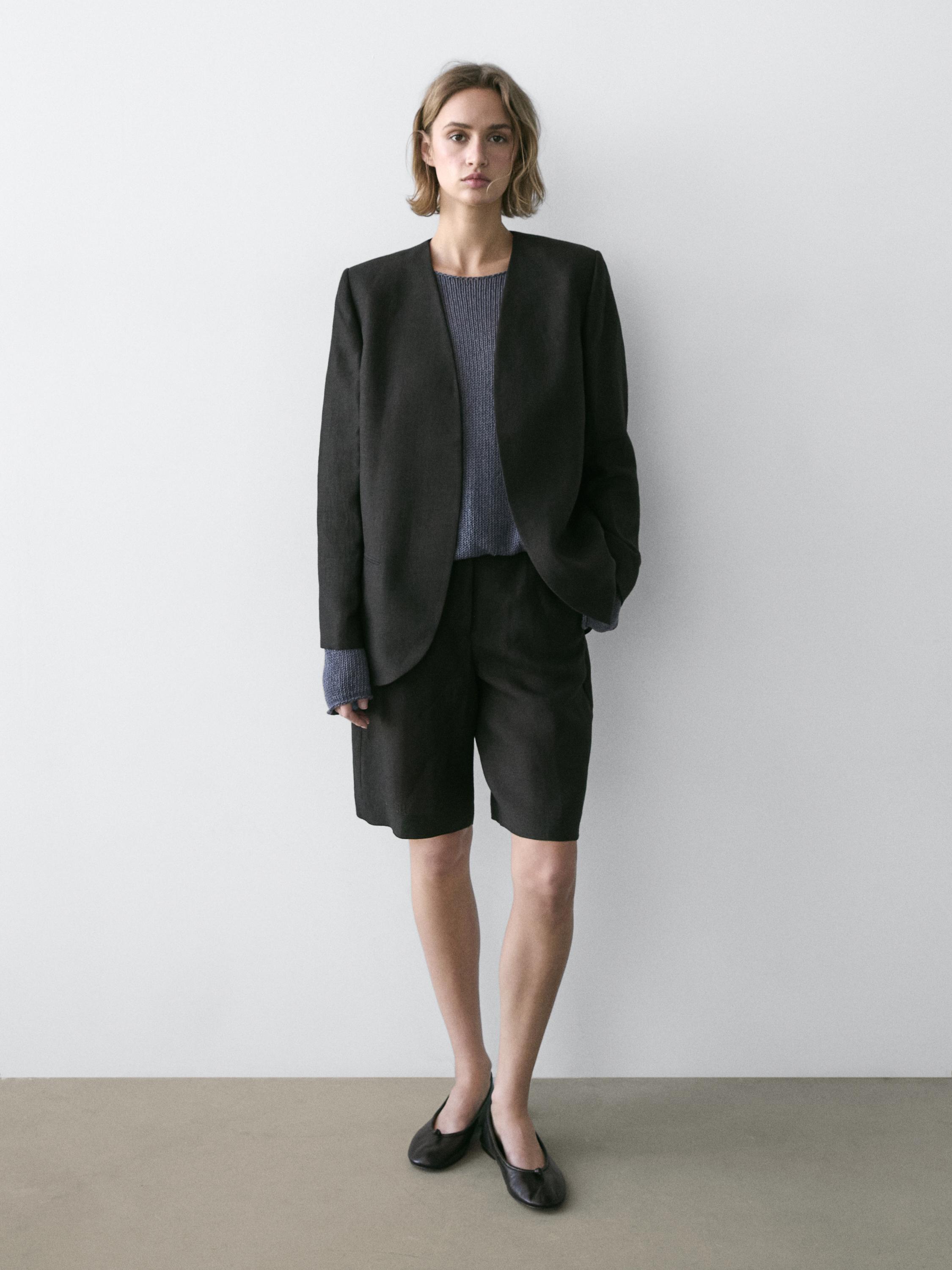 Zwarte blazer, grijs T-shirt en zwarte bermuda.