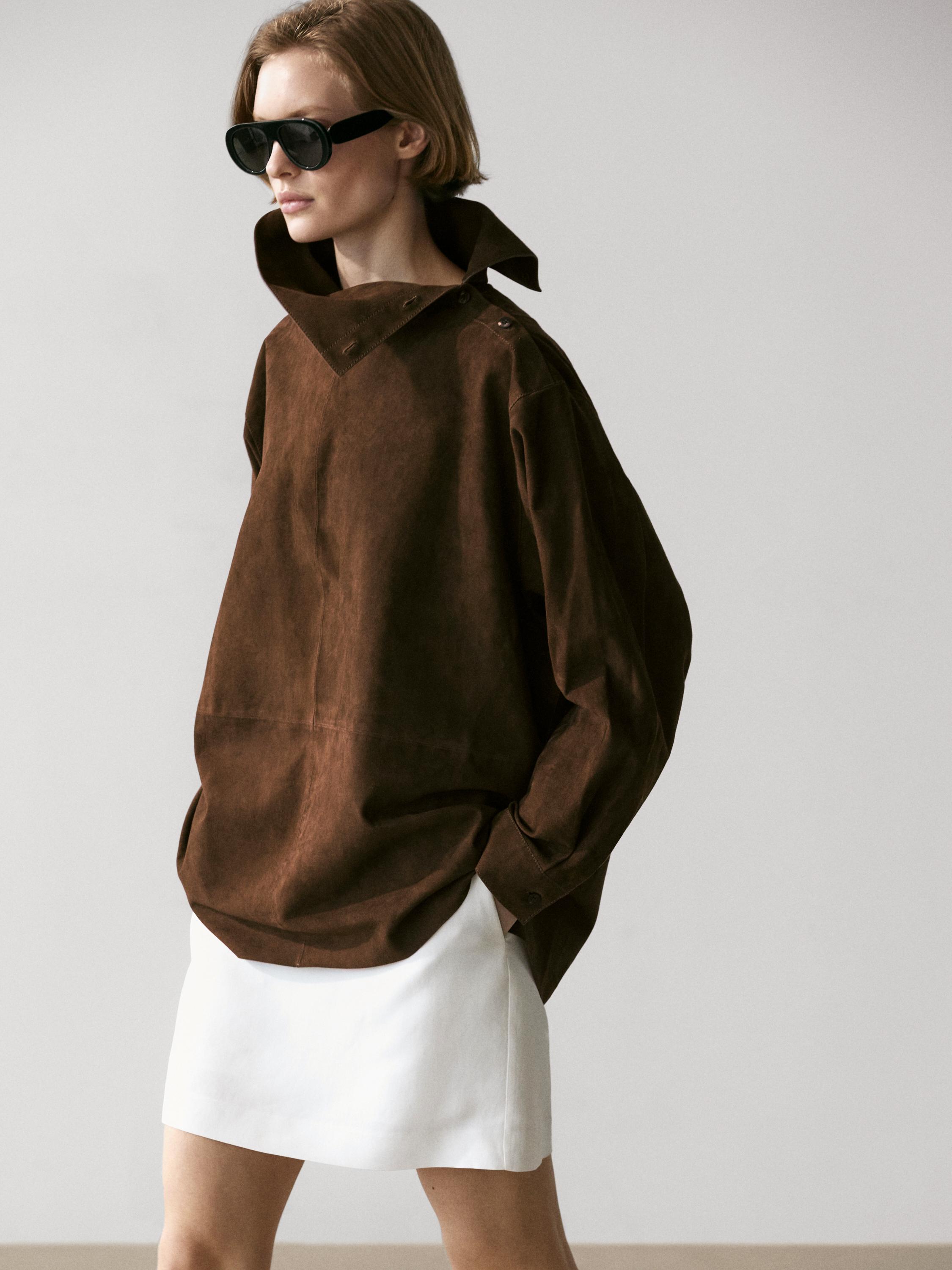 Bruine blouse met hoge hals en witte korte rok.