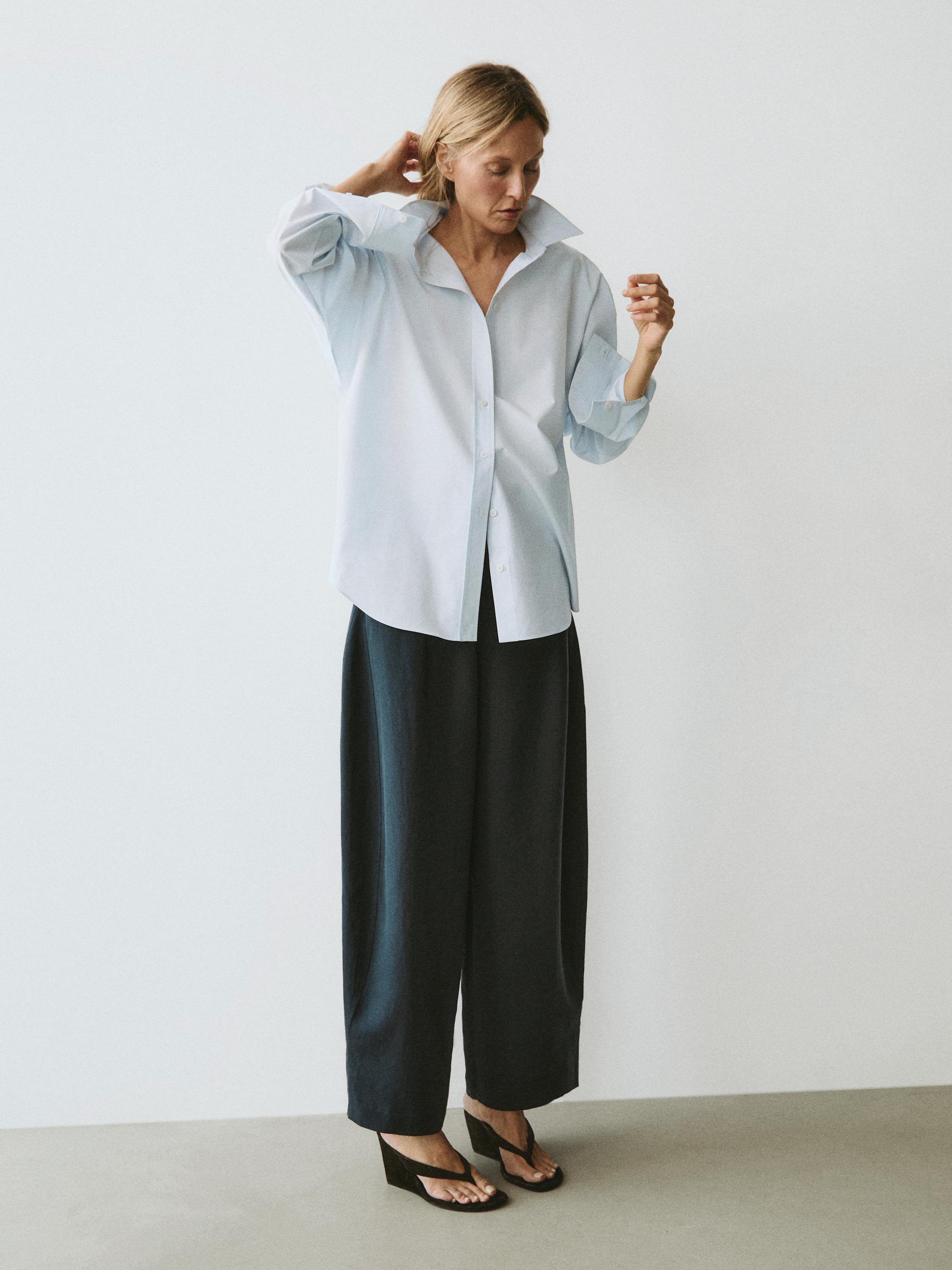 Conjunto de camisa celeste de botones y pantalones anchos negros.