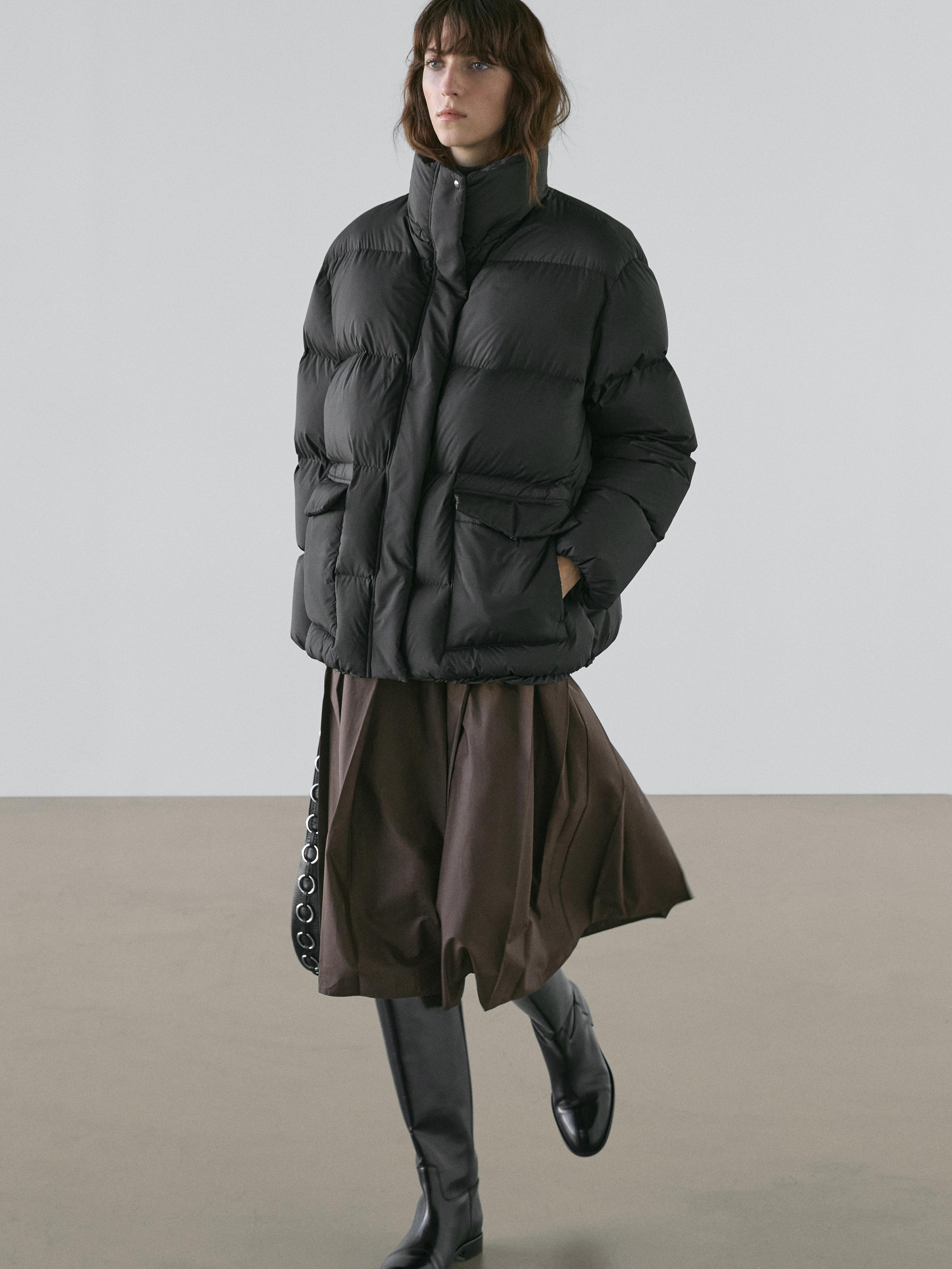 Mustast polsterdatud jakist koosnev komplekt esikäetaskutega ja pruun seelik, mustad kõrged saapad.