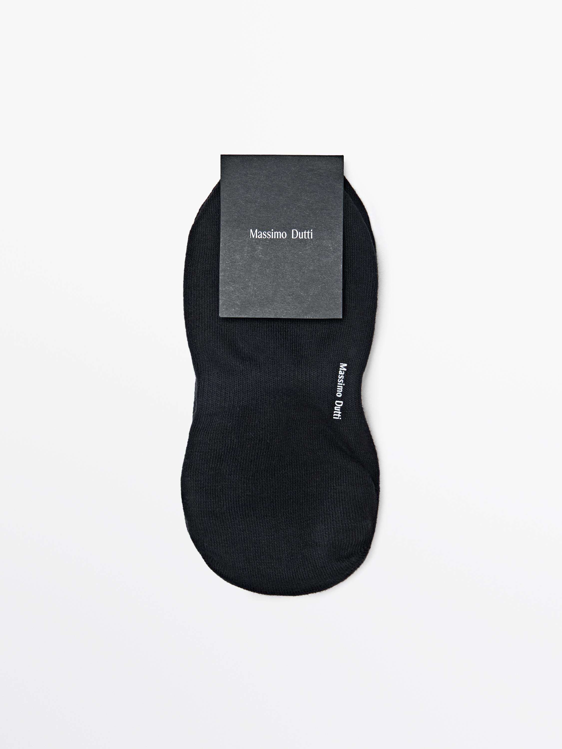 Vue de face d'une chaussette noire avec le texte "Massimo Dutti" sur le côté.