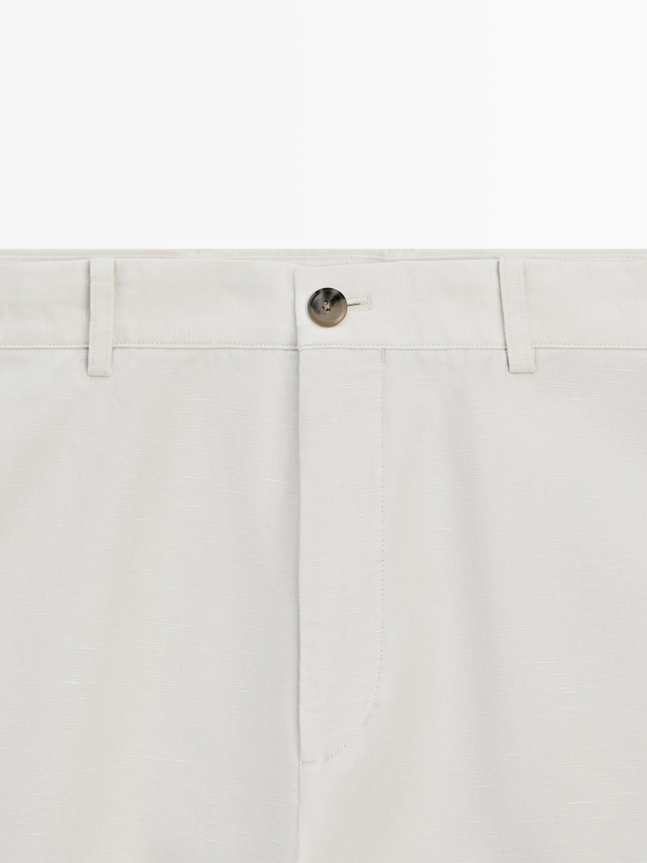 Pla mitjà de pantalons blanc trencat amb botó frontal i travetes per a cinturó.