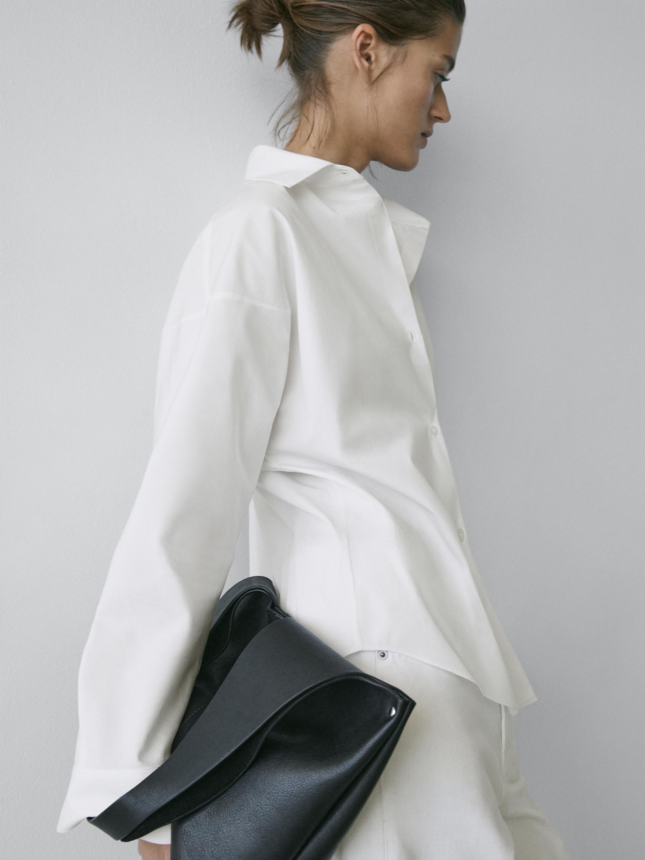 Plan moyen d'une chemise blanche à col classique avec pinces visibles.