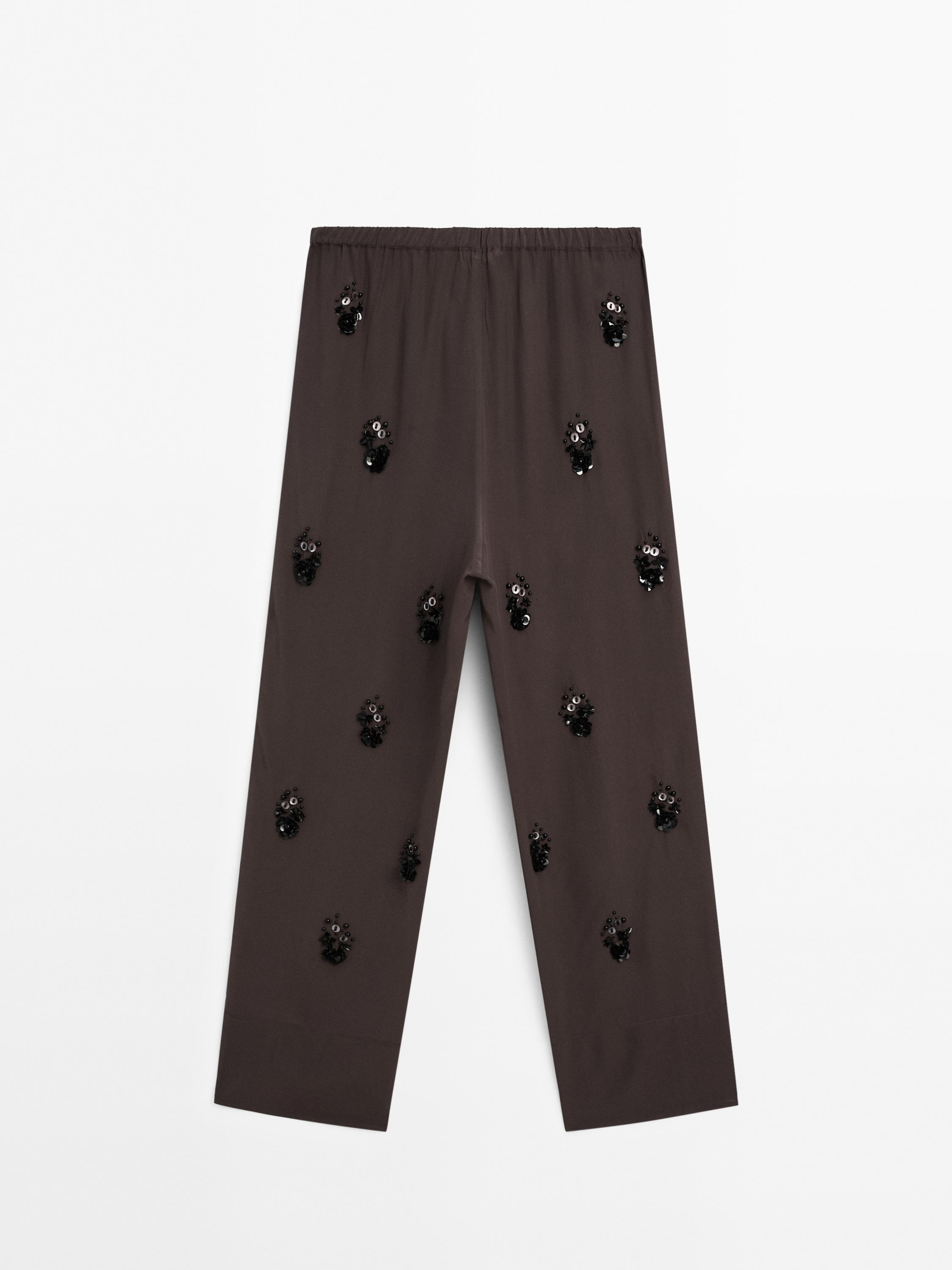 Flowing trousers with floral appliqués