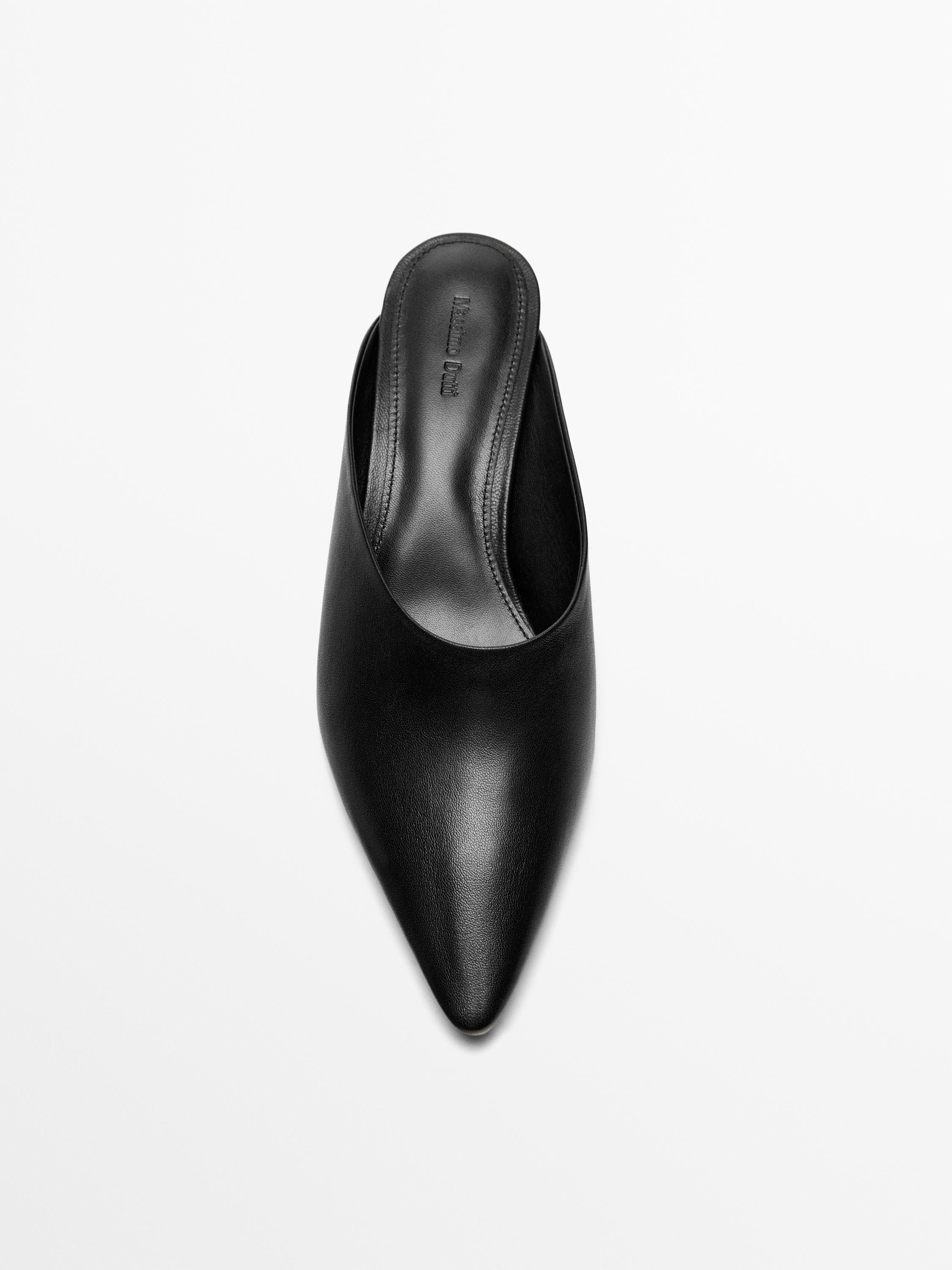 Vista superior de zapato mule negro con punta afilada y tacón cuña. Texto visible en plantilla: "Massimo Dutti".