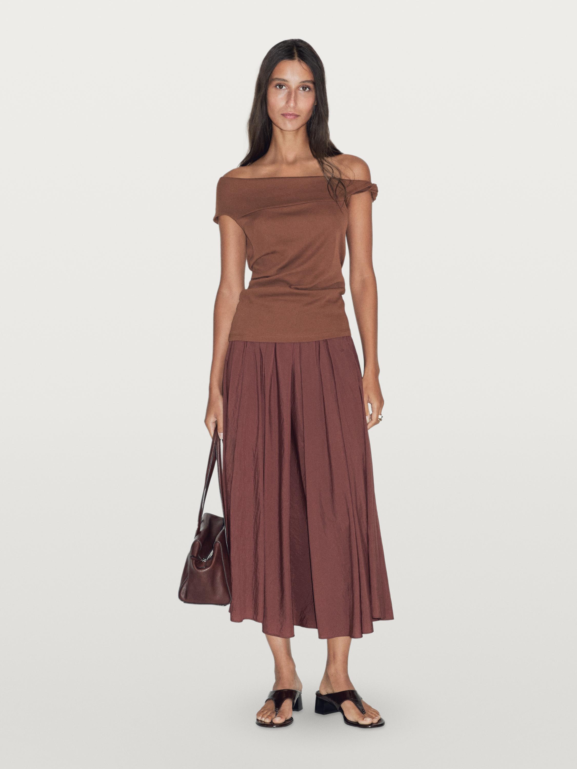 Komplet: brązowy drapowany top z wiązaniem i długa brązowa plisowana spódnica.