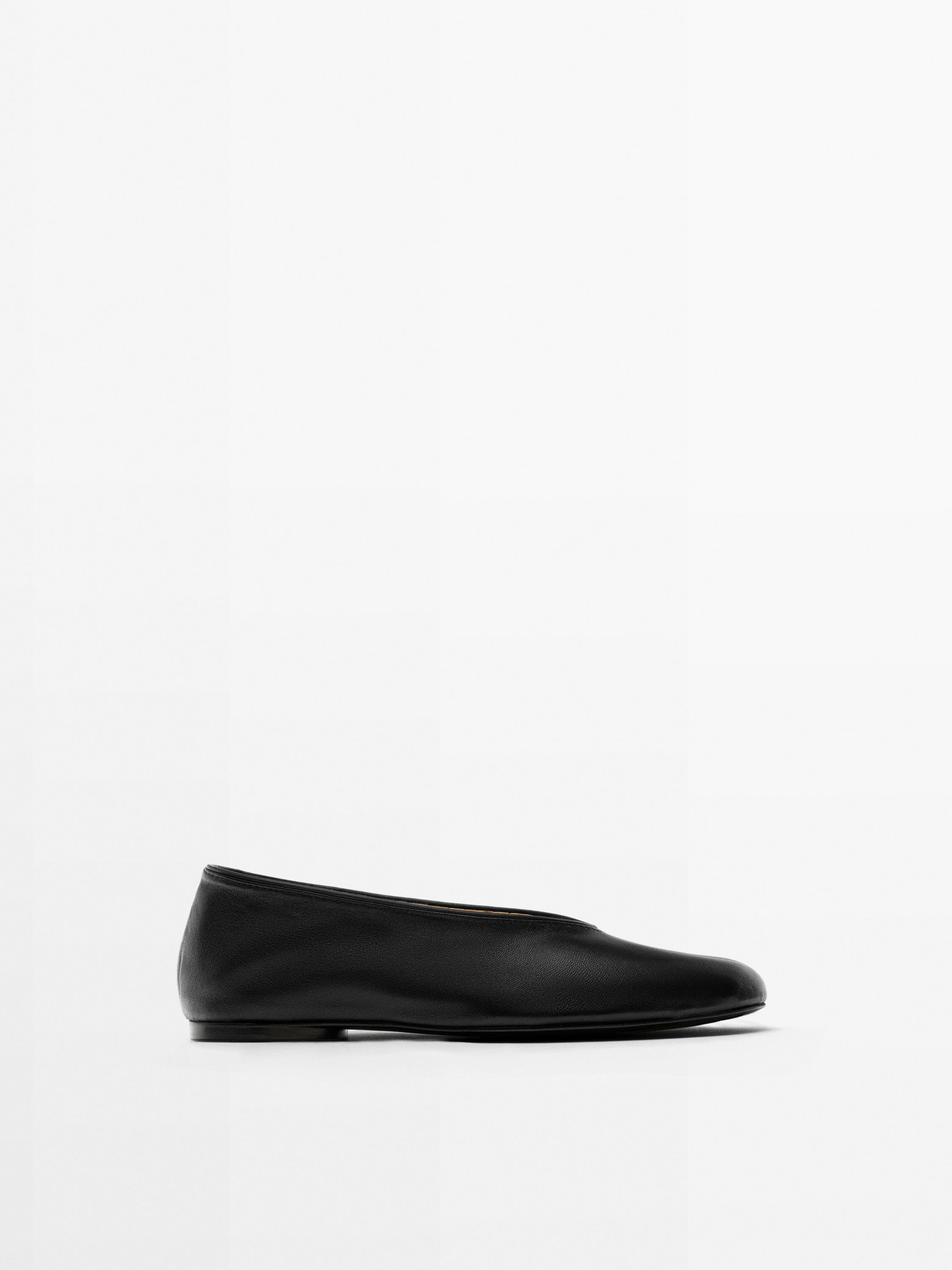 Side view of a black ballet flat with a simple design and a round toe.