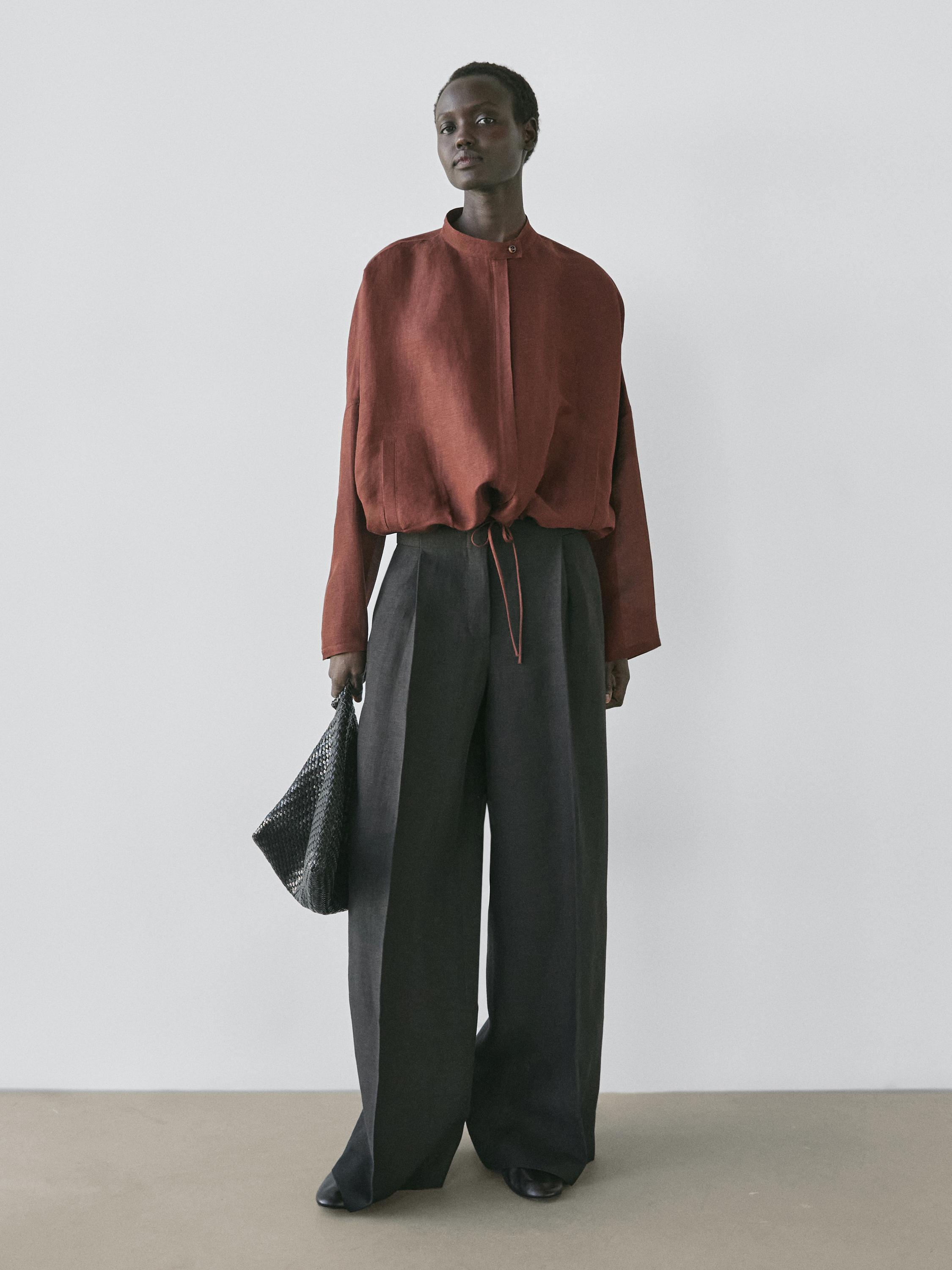 Conjunto de chaqueta bómber marrón con cuello redondo y pantalones anchos grises.