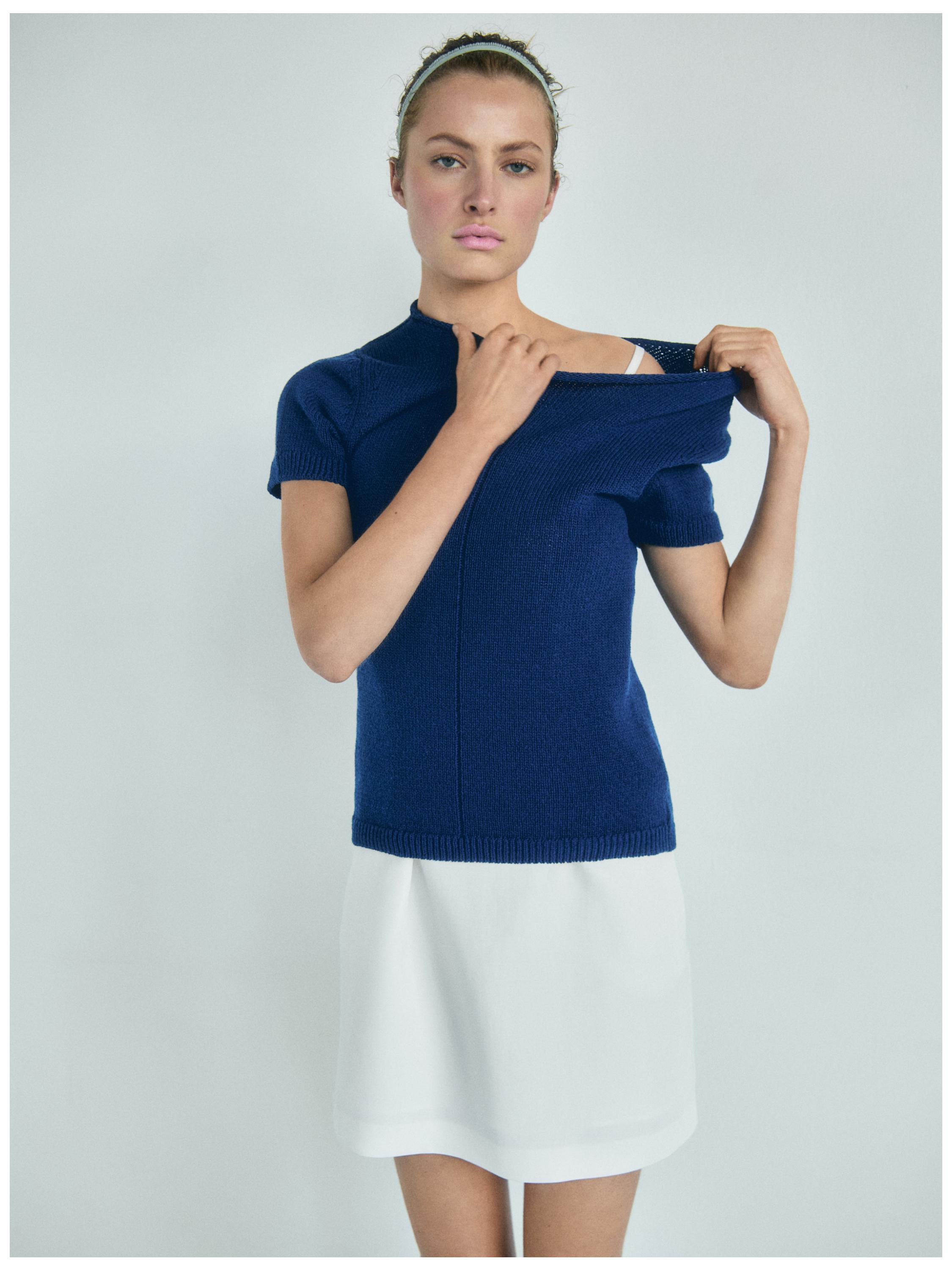 Σετ από κοντομάνικο μπλε πουλόβερ και κοντή λευκή φούστα.