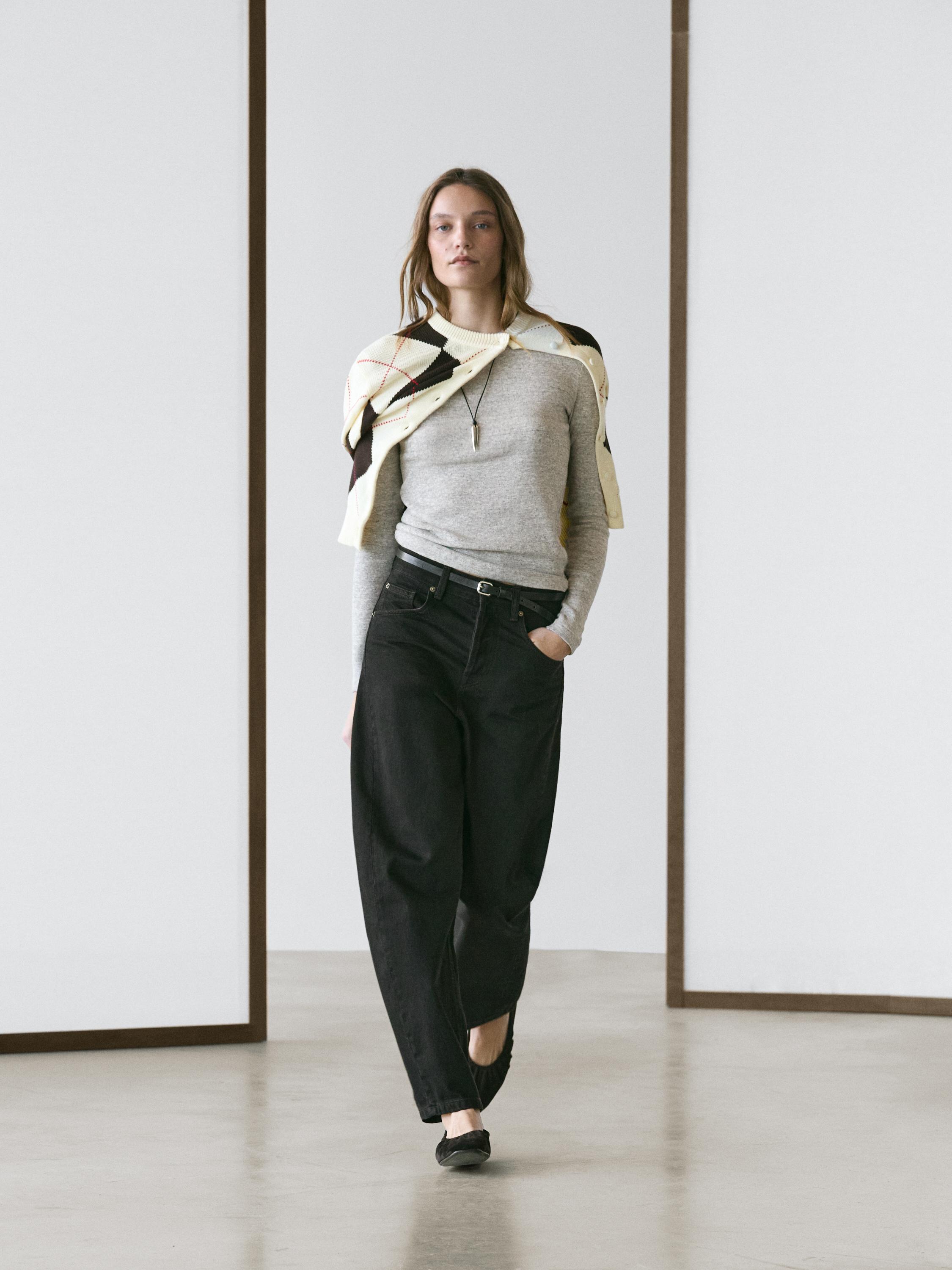 Conjunto de jeans color chocolate de corte balloon fit y tiro medio, suéter gris y chaleco con diseño geométrico en tonos claros.