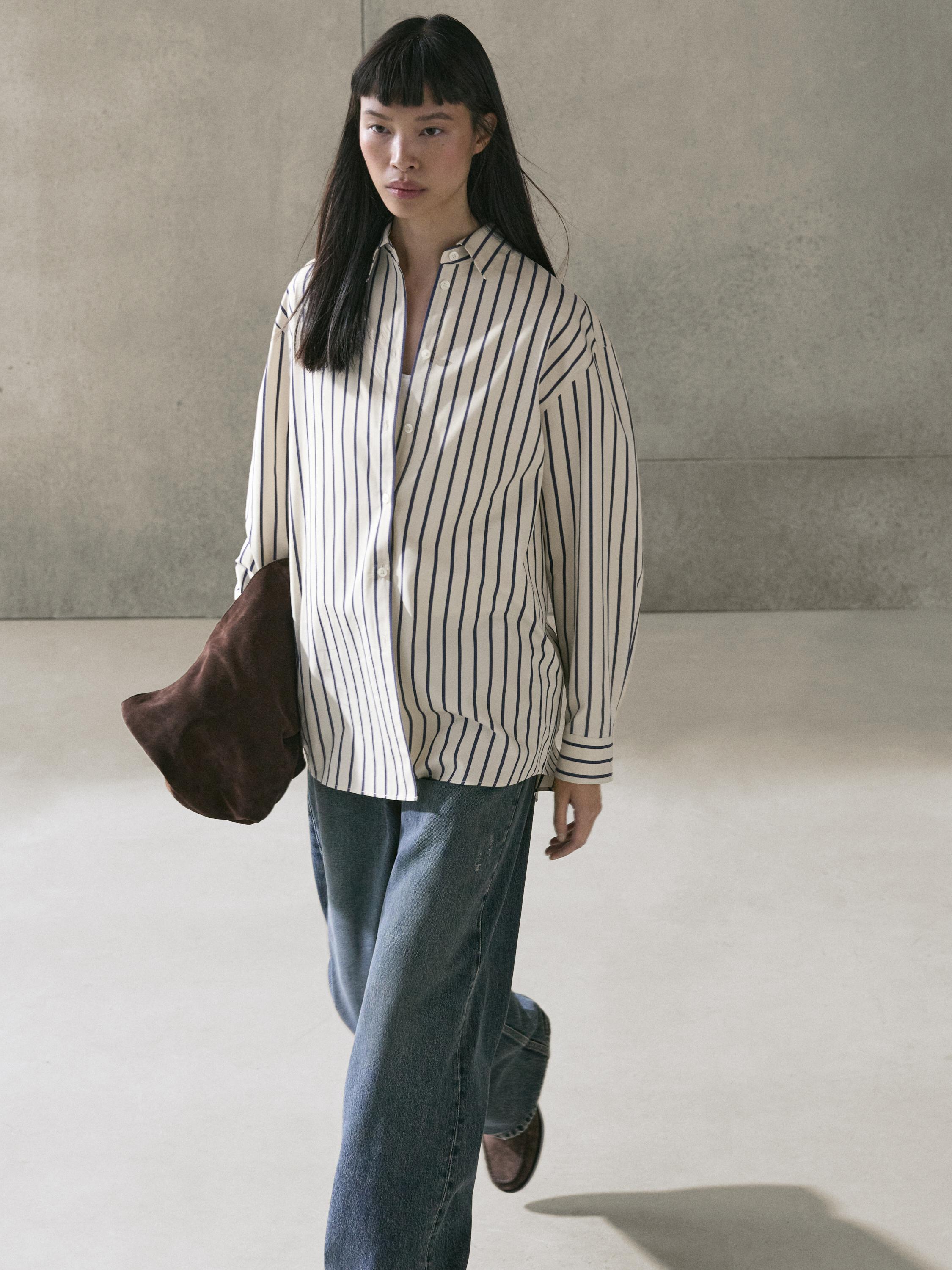 طقم قميص مخطط عمودي أبيض وأسود مع جينز أزرق متوسط واسع الساق وخصر مرتفع.