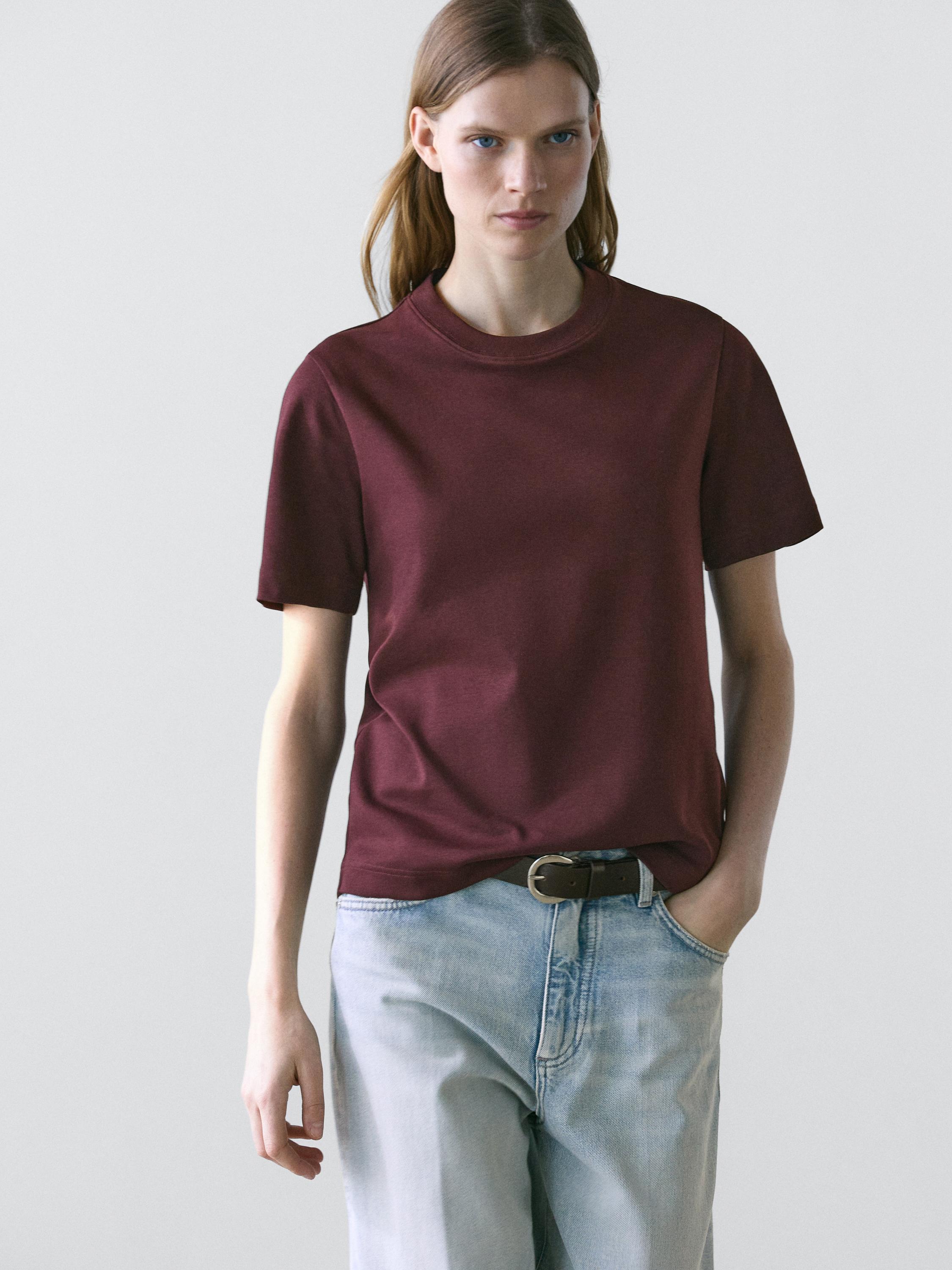 Σετ από μπορντό κοντομάνικο T-shirt με στρογγυλή λαιμόκοψη και ανοιχτόχρωμο τζιν παντελόνι.