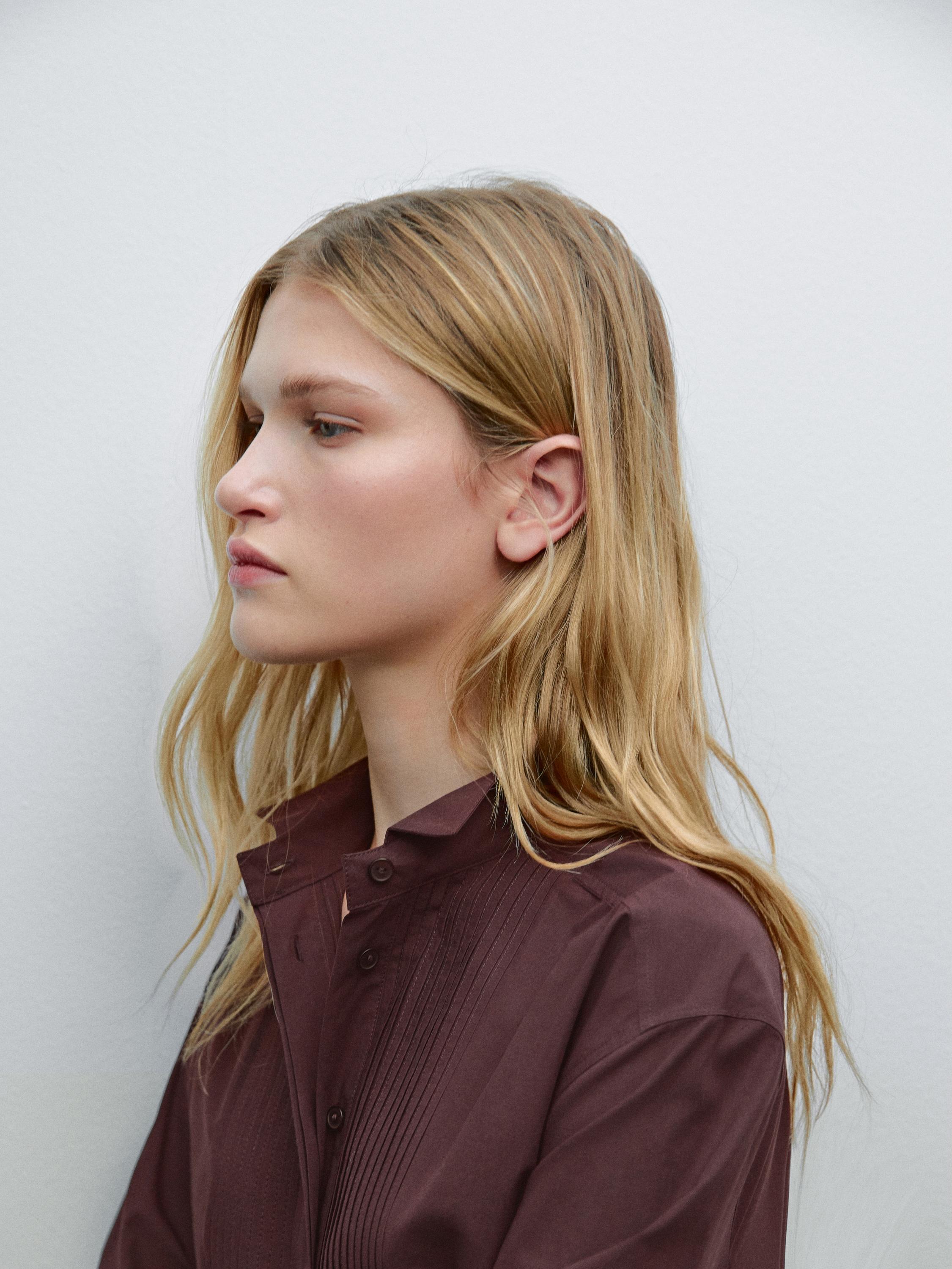 Plano medio de blusa marrón con cuello alto y pliegues frontales