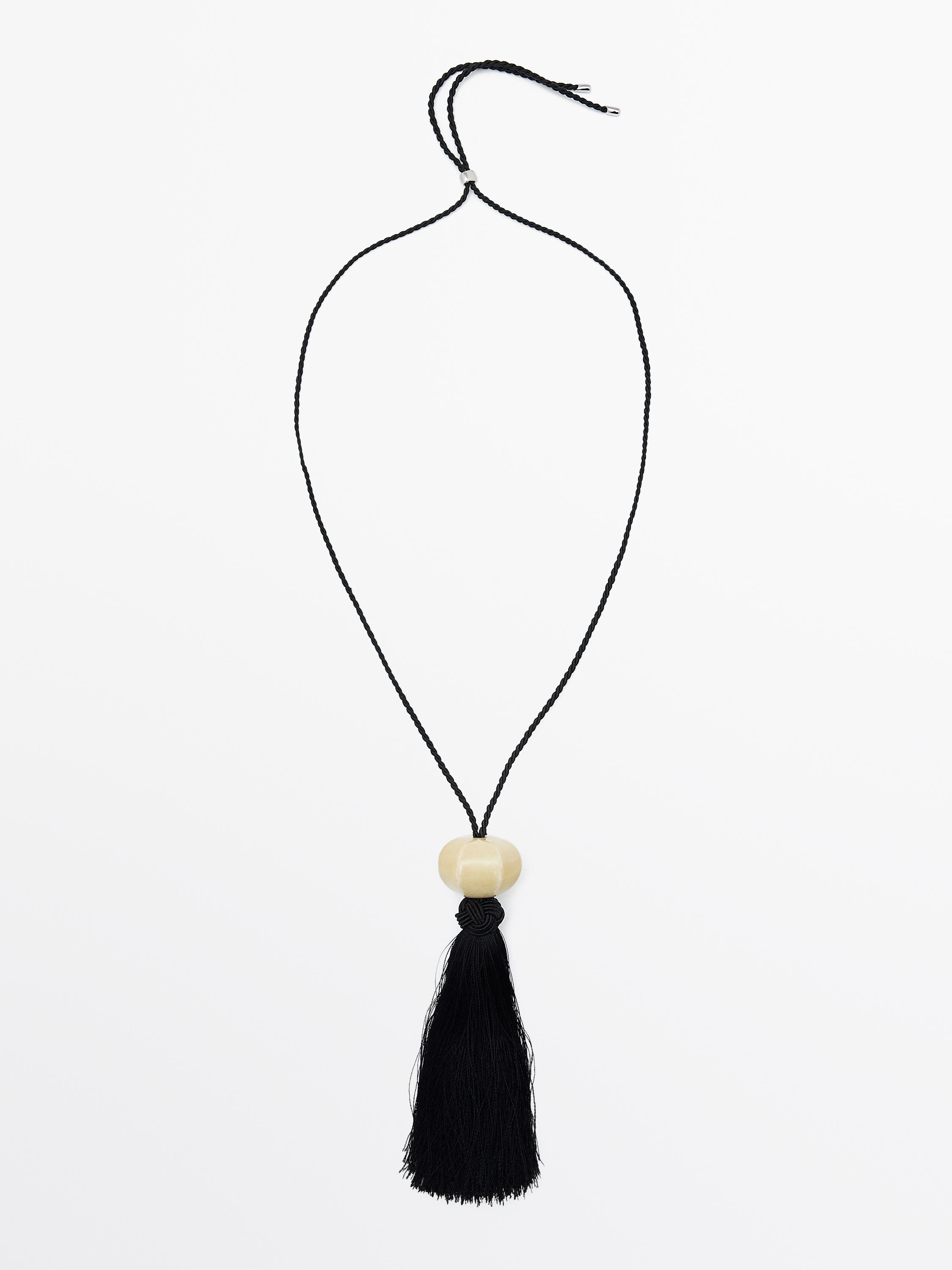 Front view of a black necklace with braided cord, beige ceramic centerpiece, and long black tassel.