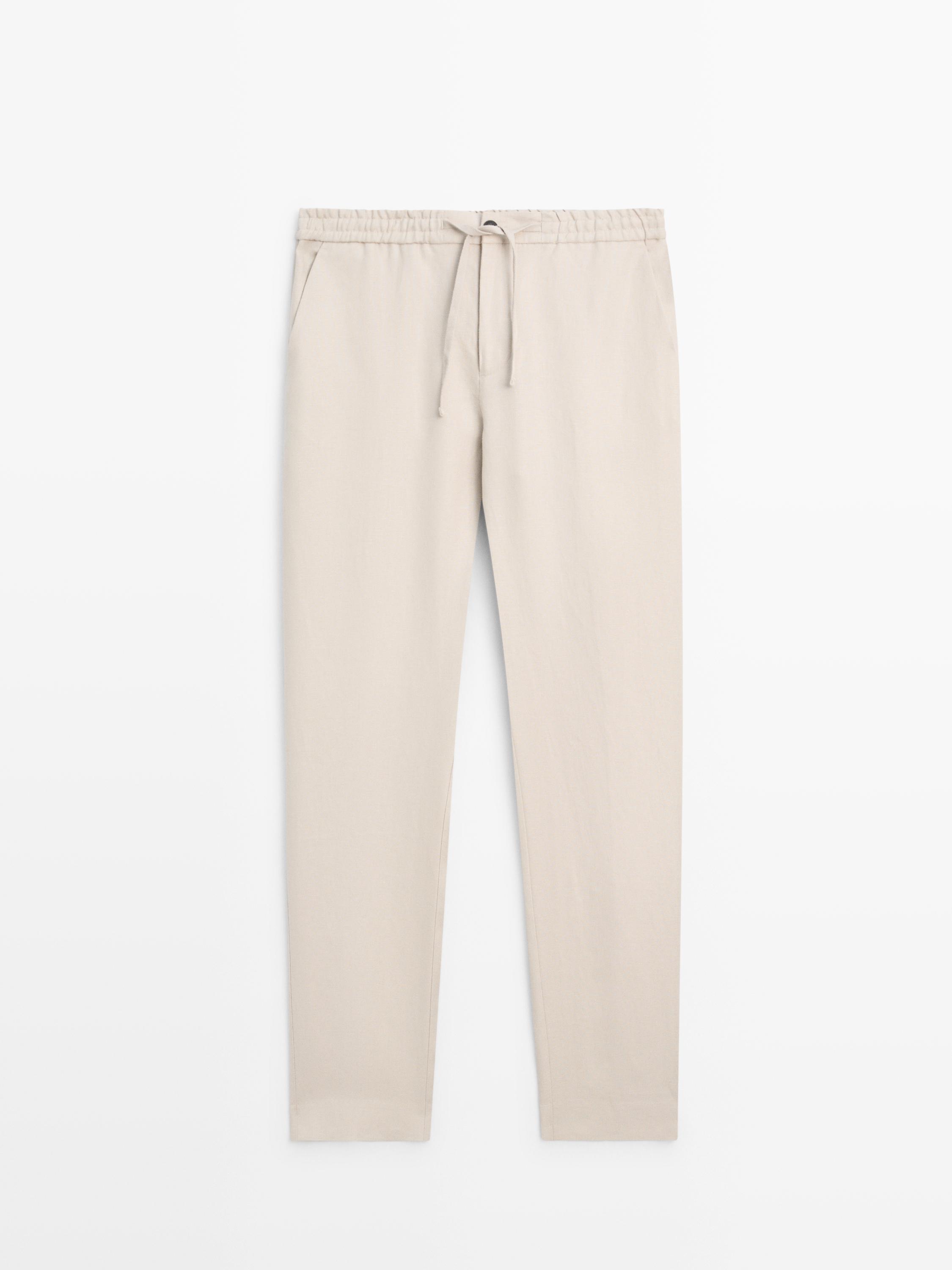 Vue de face d'un pantalon beige avec taille élastique et cordon de serrage ajustable, poches latérales.