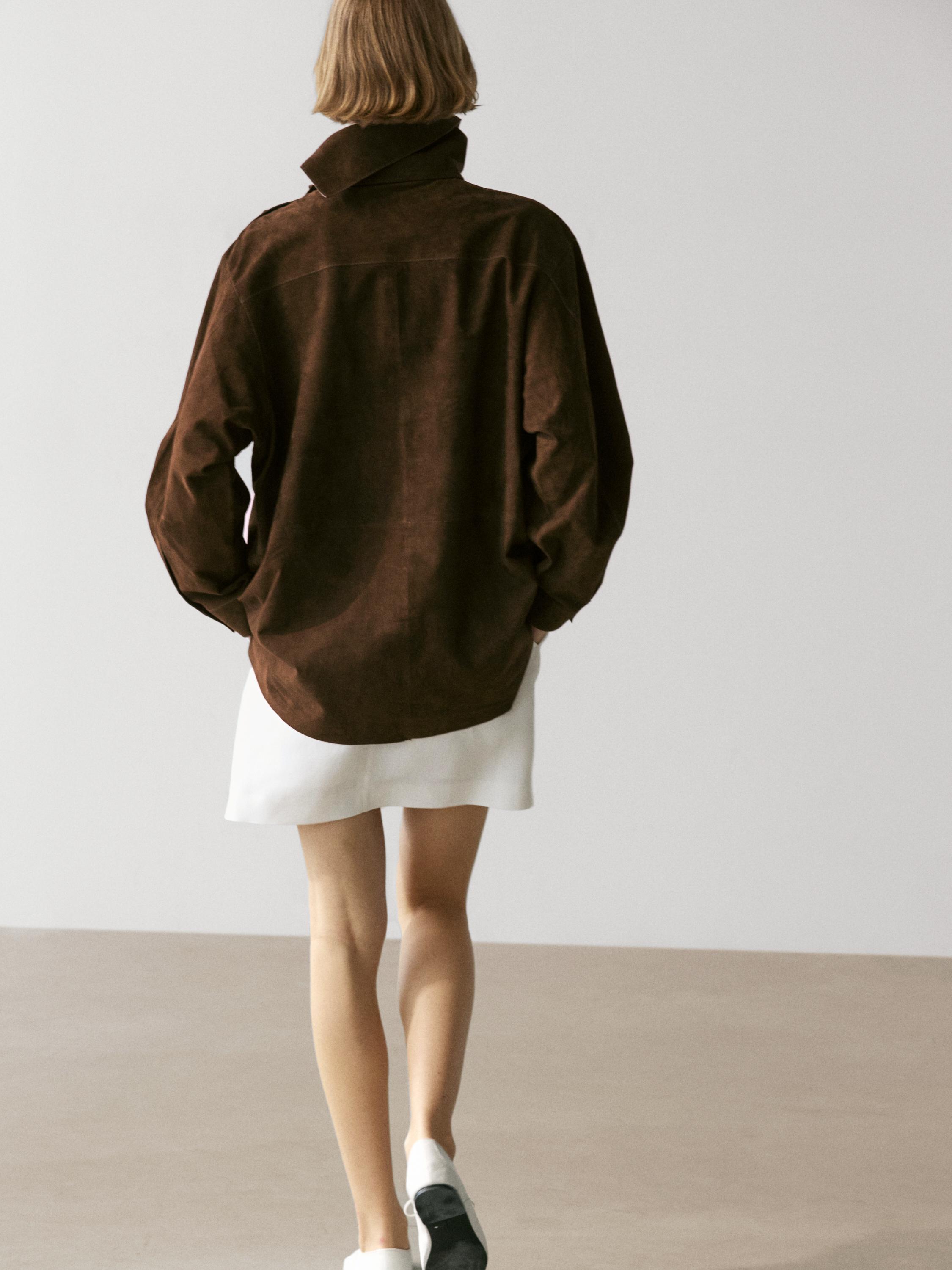 Conxunto de blusón marrón de colo subido e saia branca curta, vista posterior.