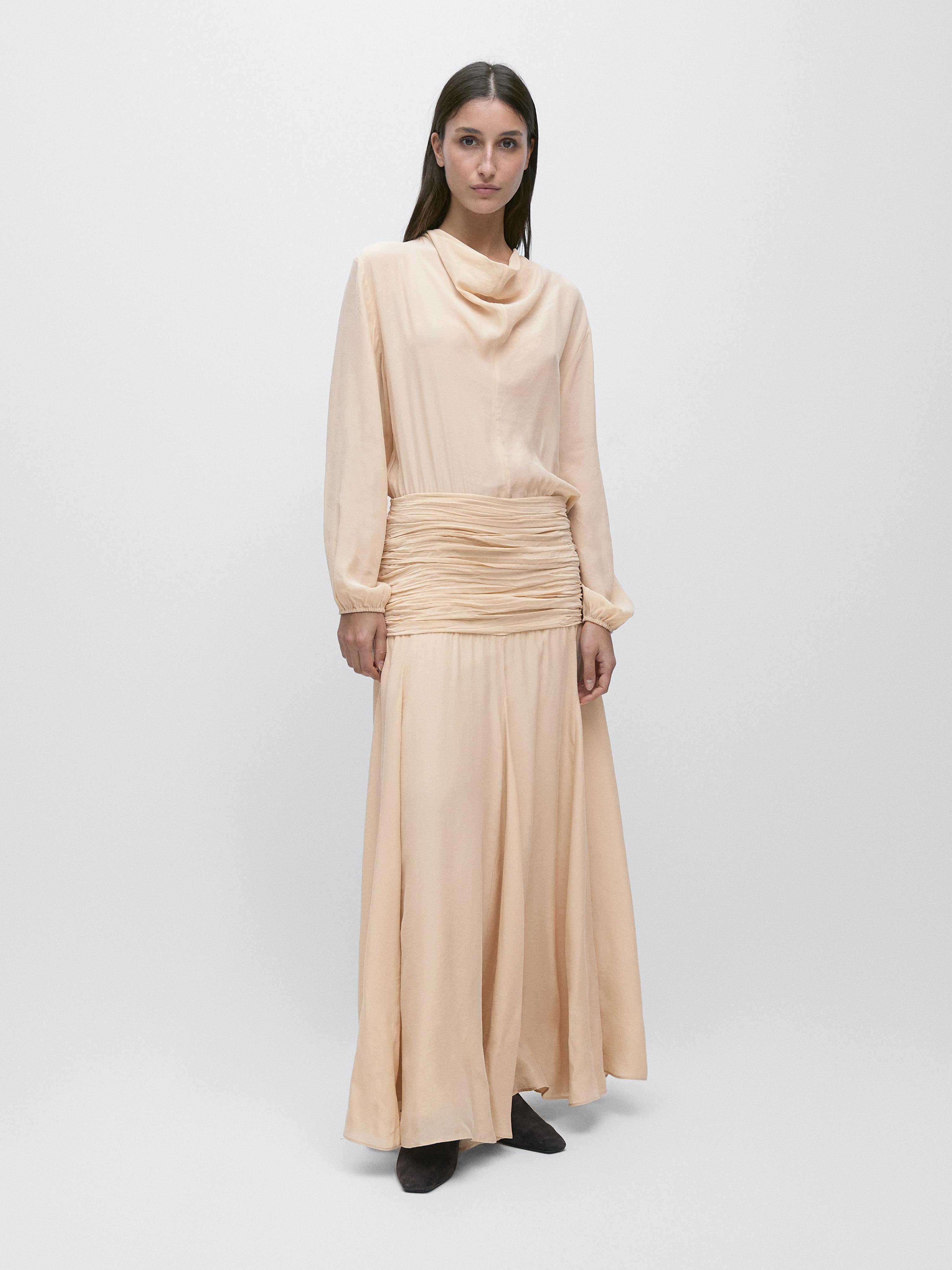 Ensemble de robe longue fluide couleur avec détail de volant à la taille et col drapé.