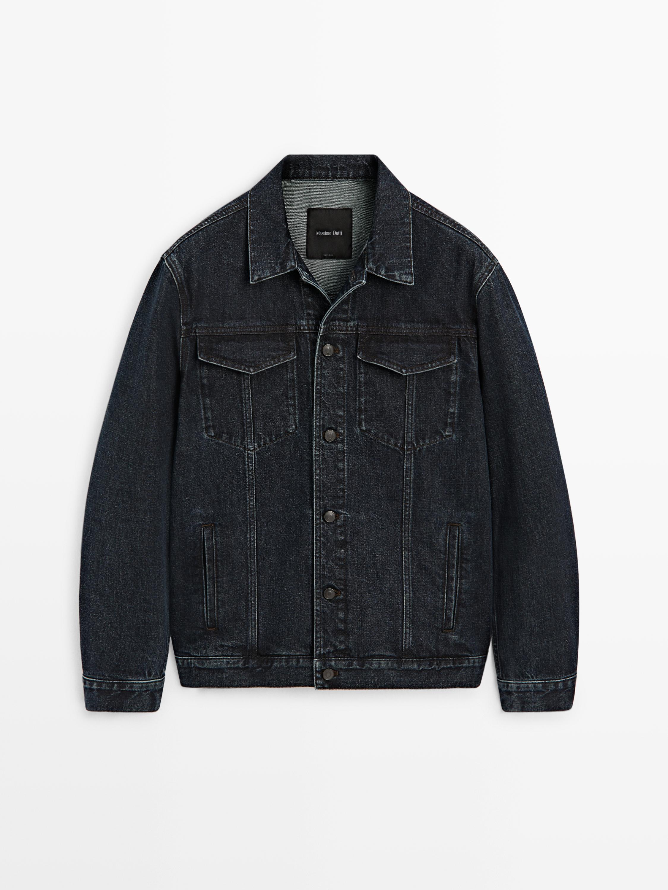 Vista frontal de casaco de ganga azul-marinho com bolsos frontais com aba e fecho de botões.