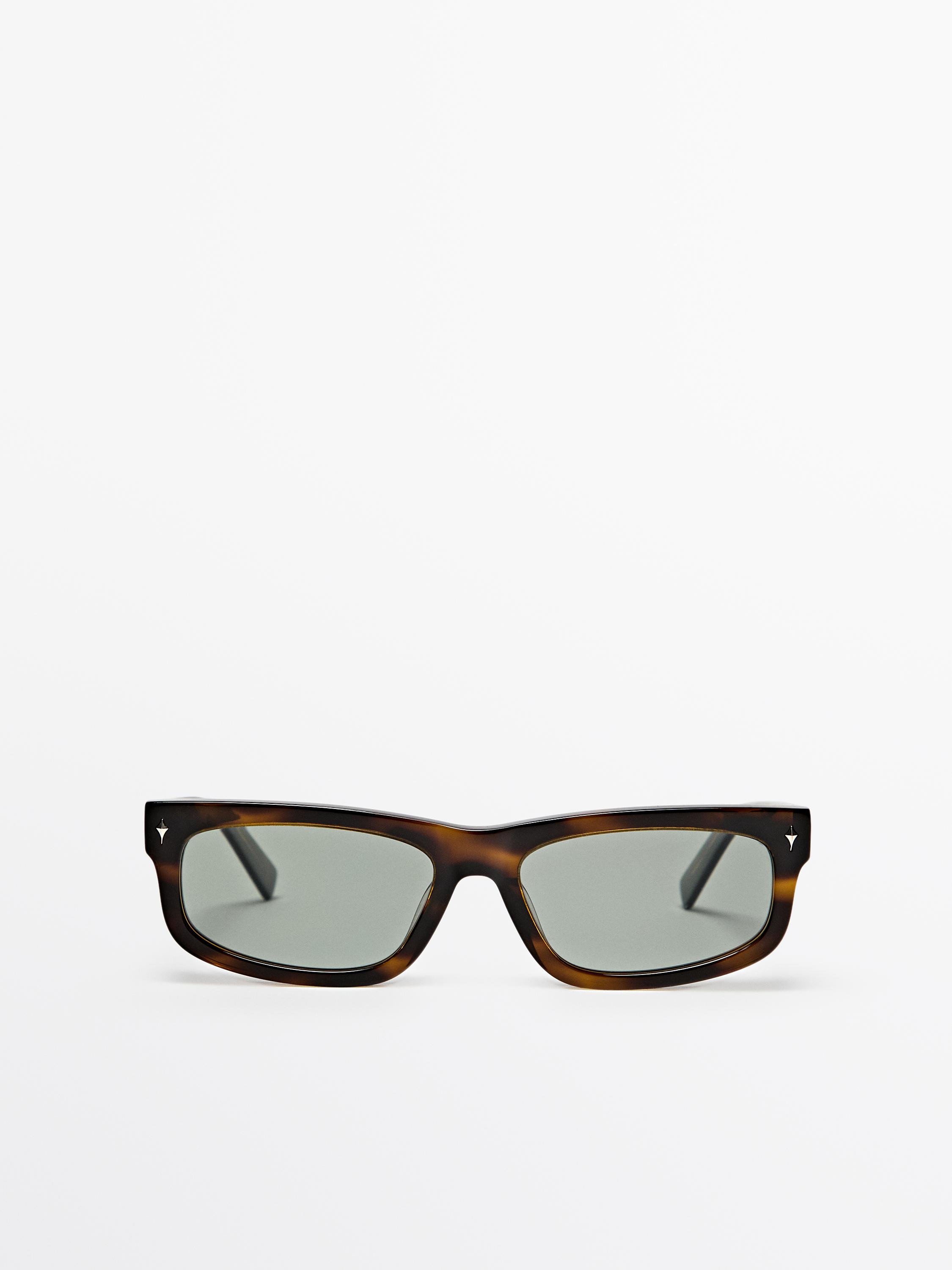 Lentes de sol cafés con armazón rectangular y micas oscuras.