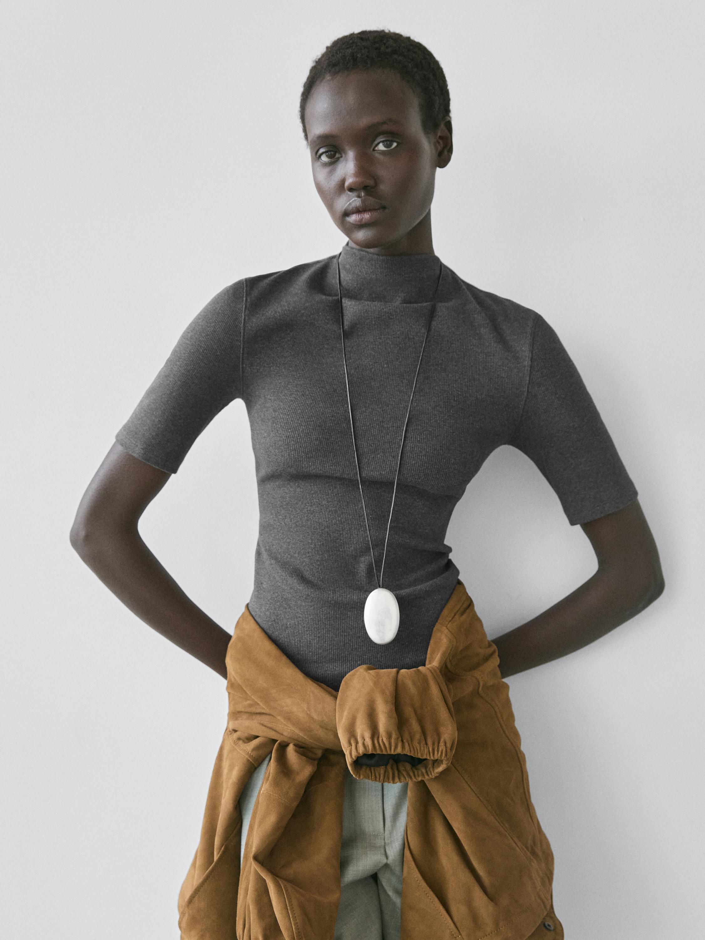 סט של חולצת טי אפורה פחם עם שרוולים קצרים וצווארון גולף, עם ז'קט חום קשור למותניים.