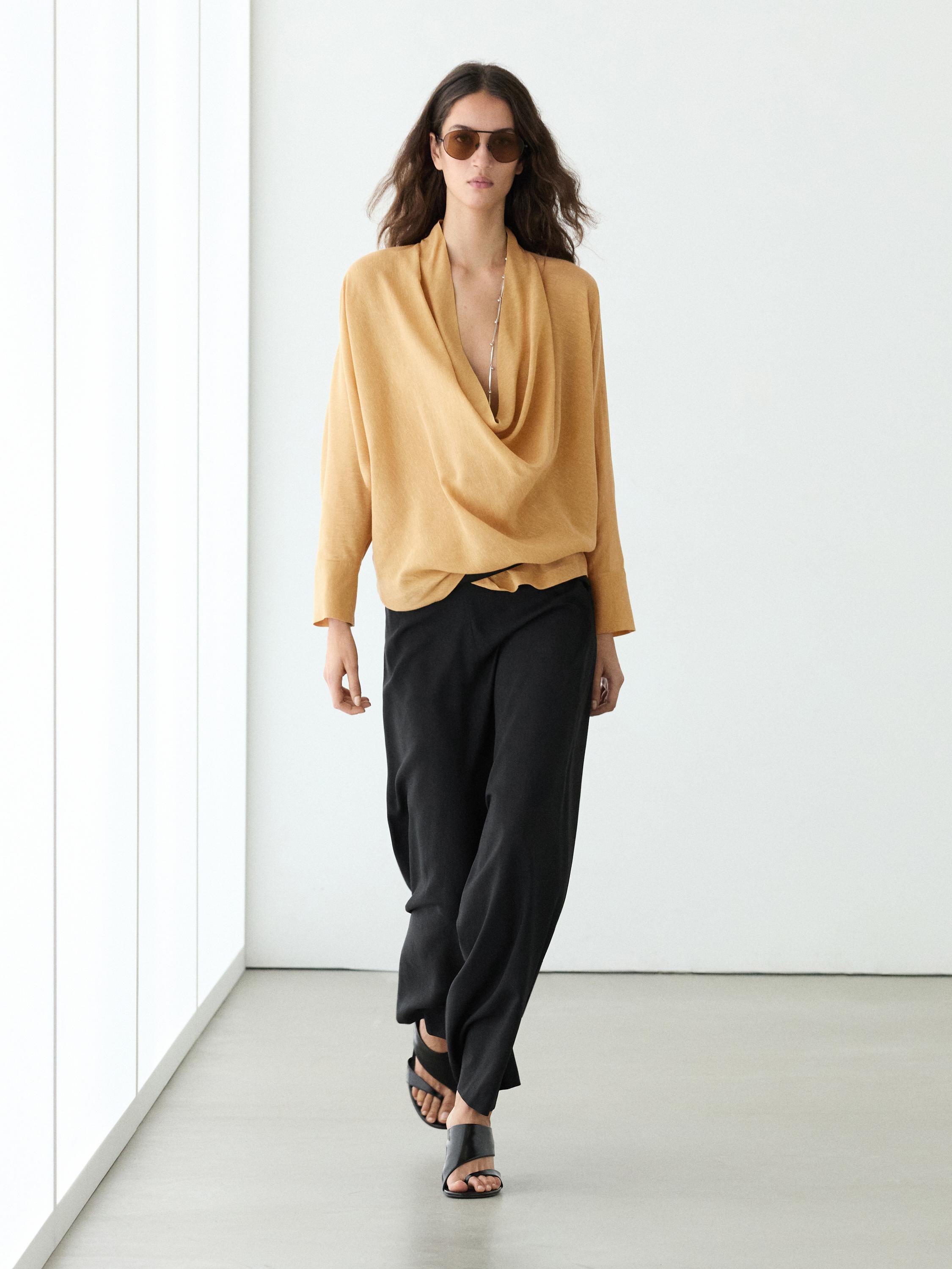 Ensemble de blouse moutarde à col bénitier et pantalon noir ample.