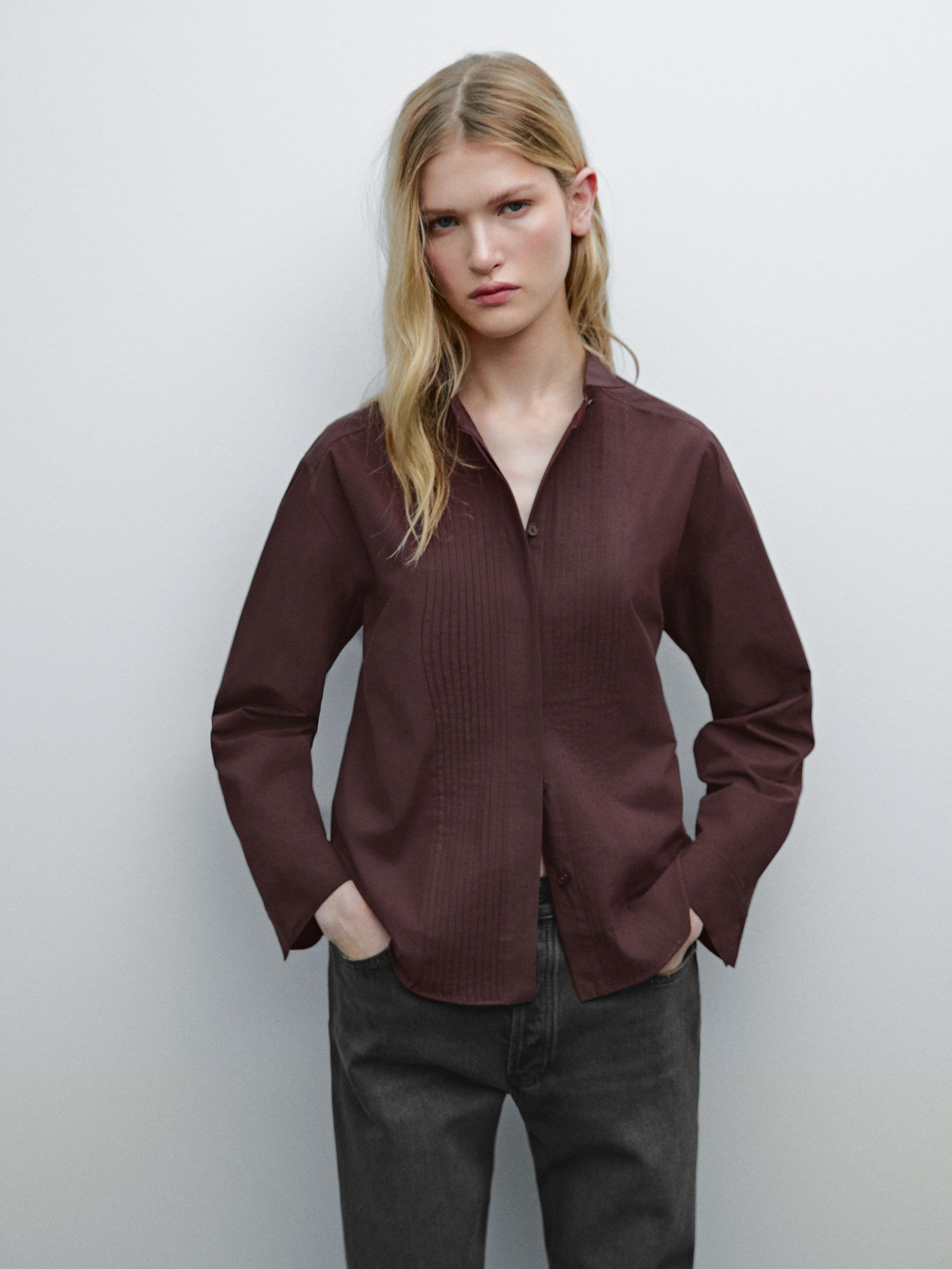 Conjunto de camisa marrón con pliegues frontales y jeans oscuros.