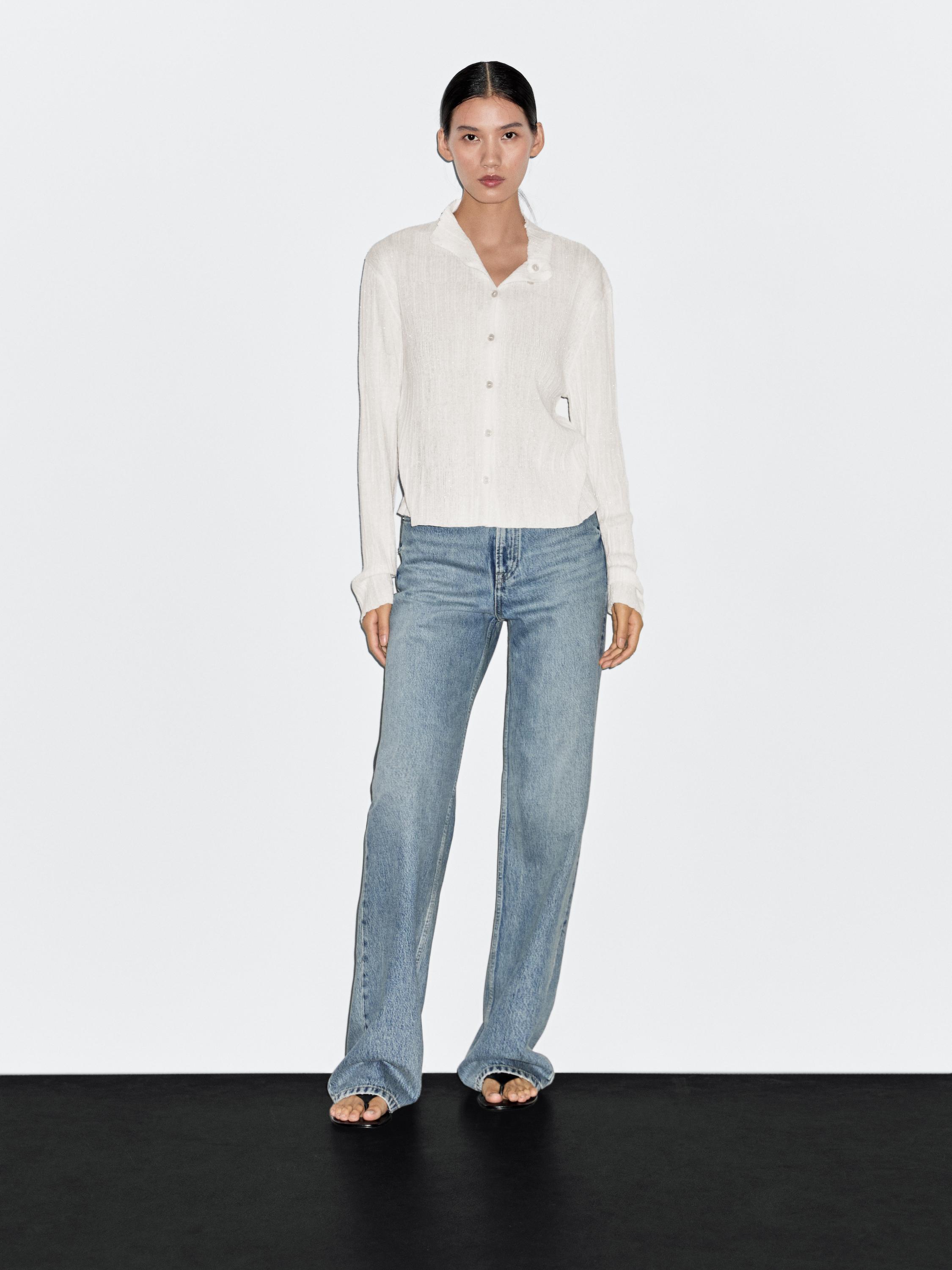 Conjunto de cárdigan crudo con botones y jeans azules de pierna recta.