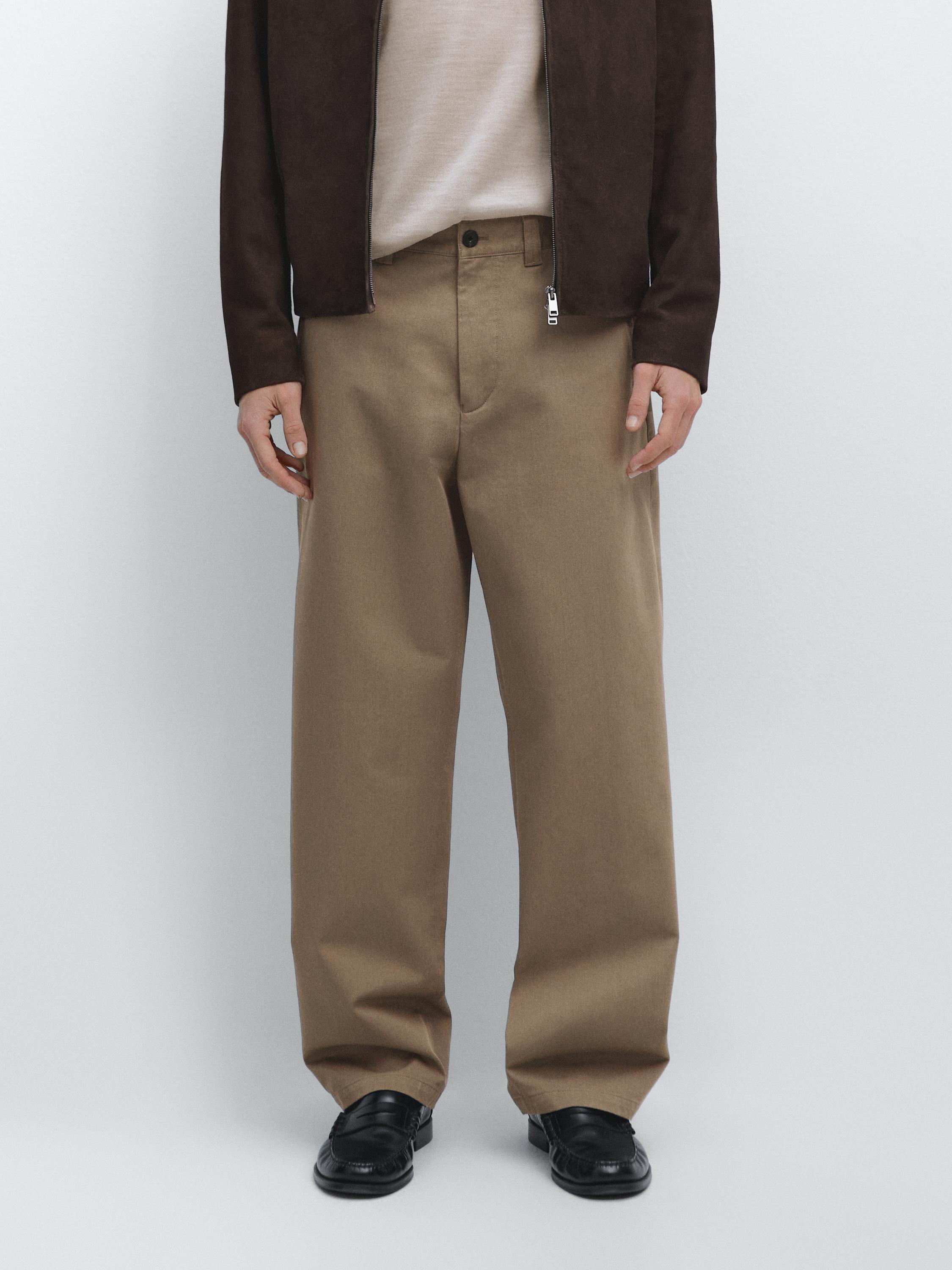 Mink relaxed fit pants set with side pockets and front button, combined with a brown jacket and black shoes.