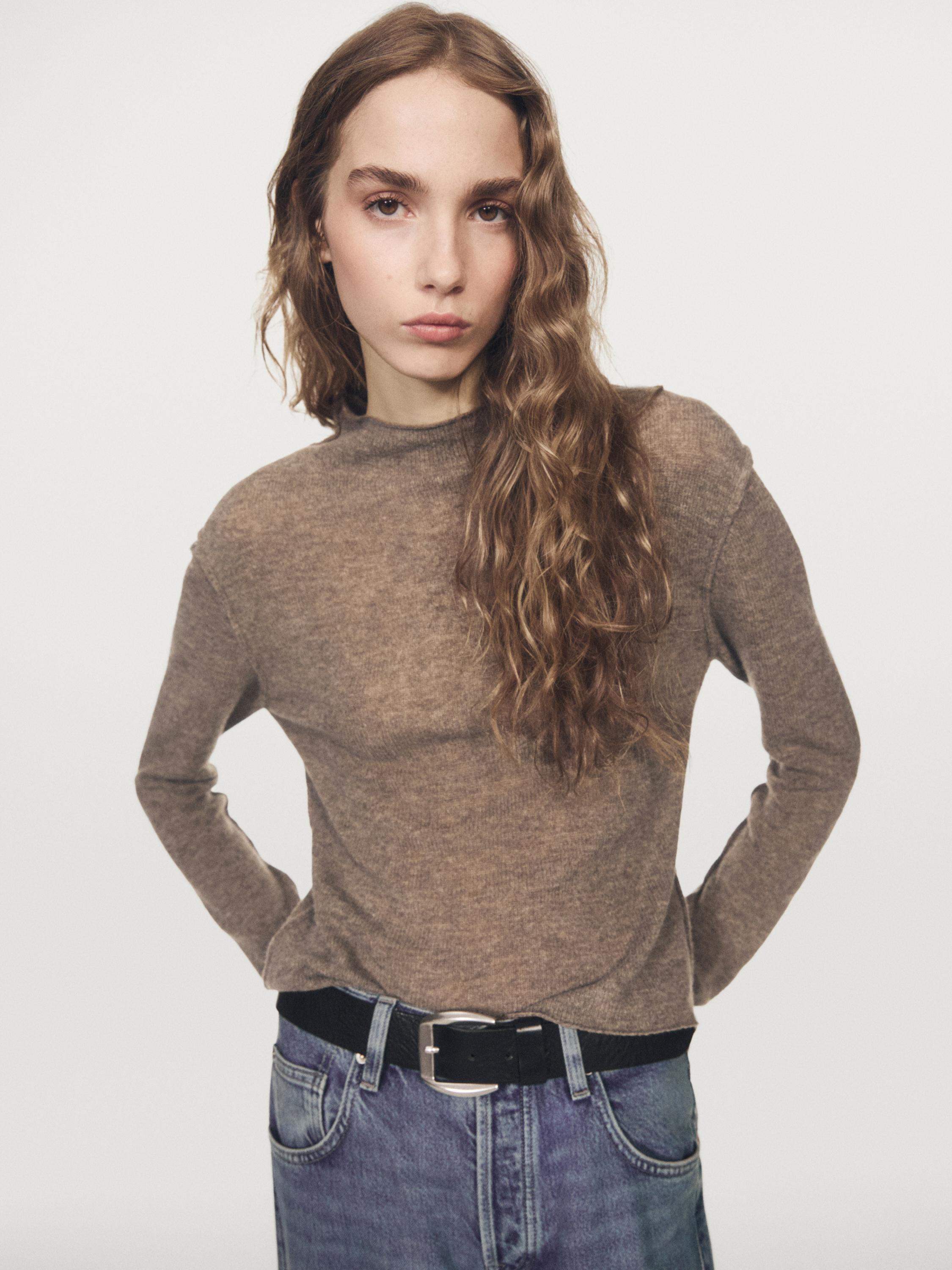 Brown turtleneck sweater set and blue jeans with a black belt.
