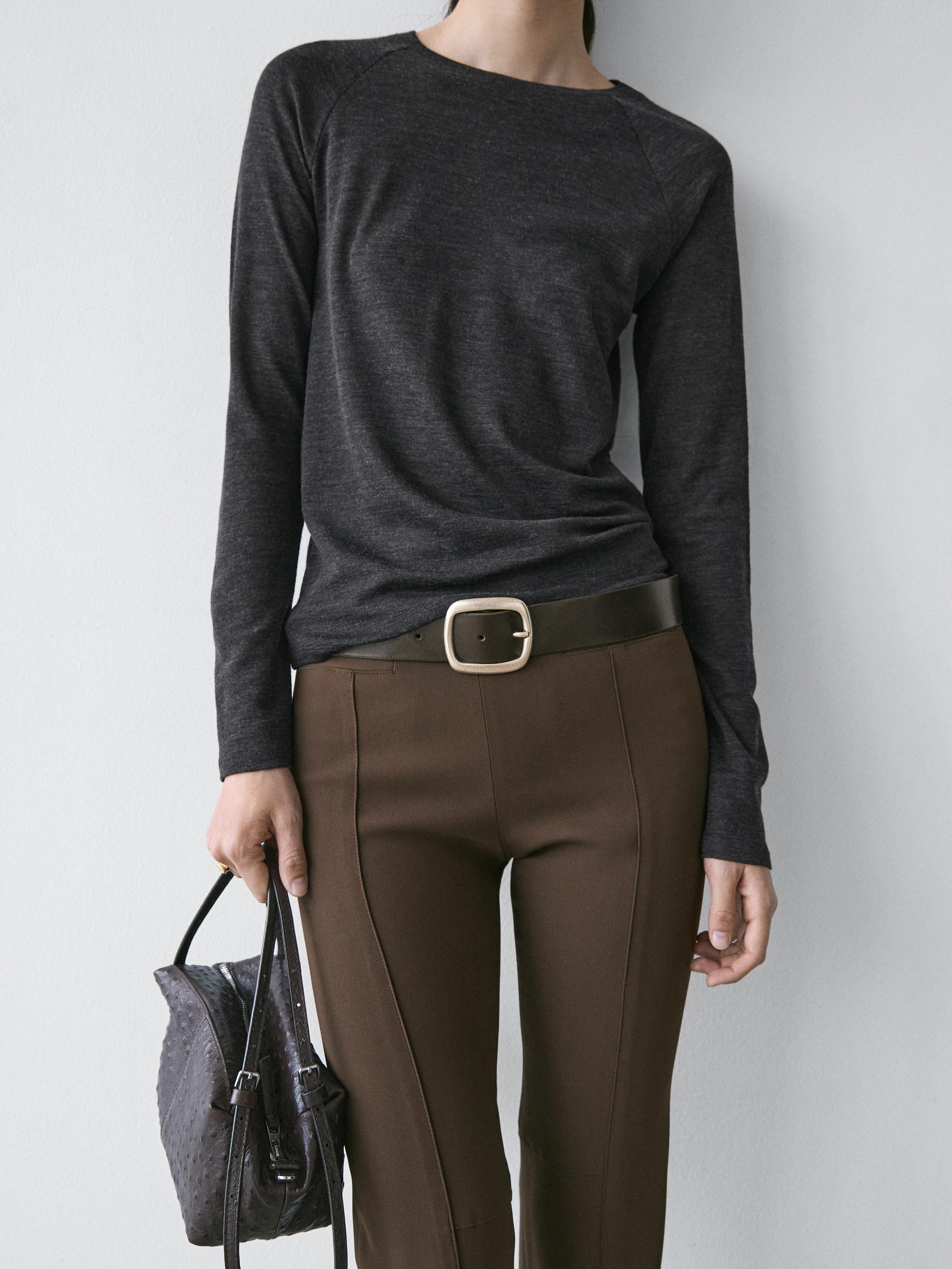 Medium shot of a long-sleeved anthracite gray t-shirt with a round neck, paired with brown pants and a black belt.