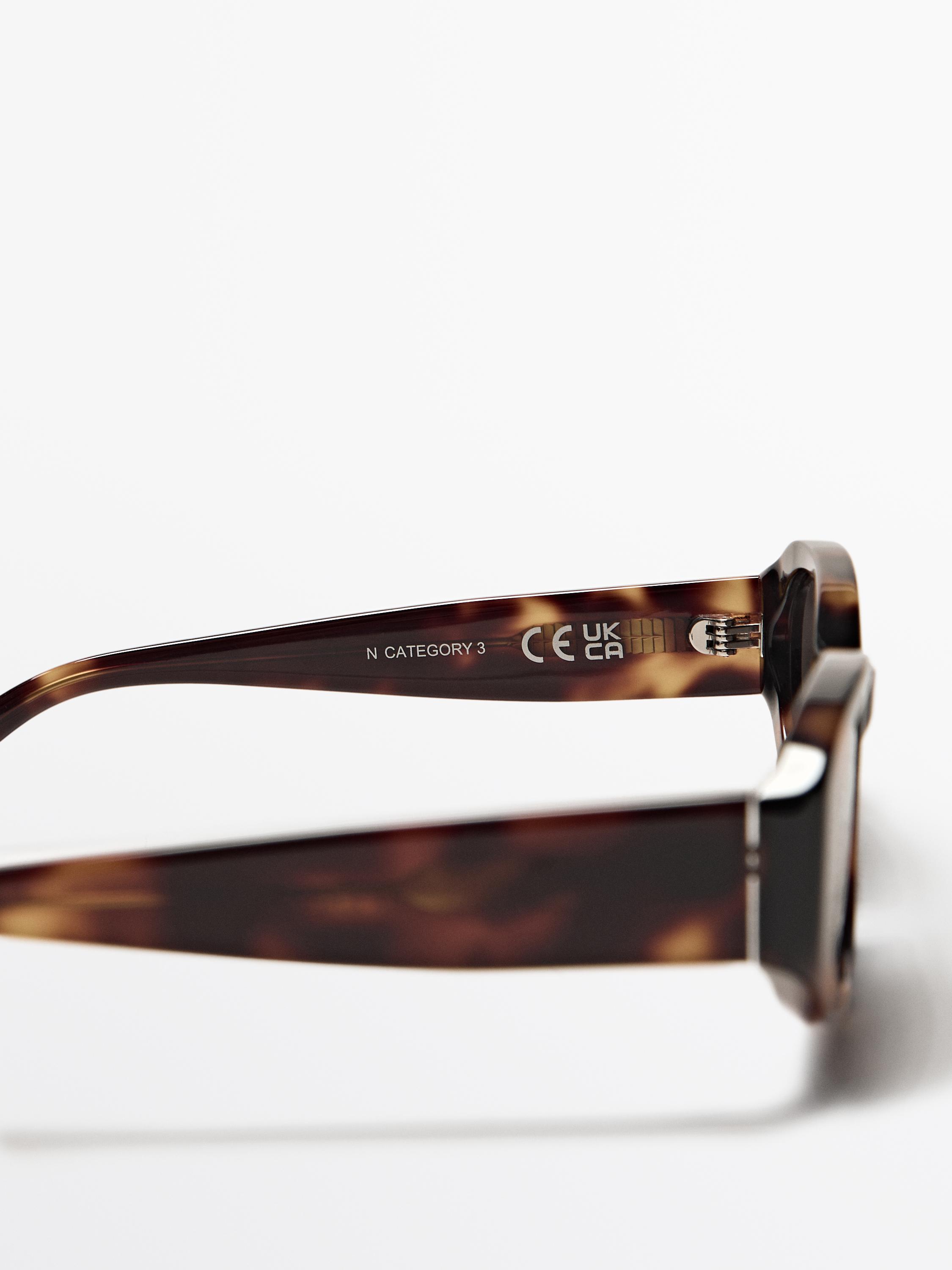 Detalle de patilla de gafas con estampado carey y texto 'N CATEGORY 3 CE UK CA'.