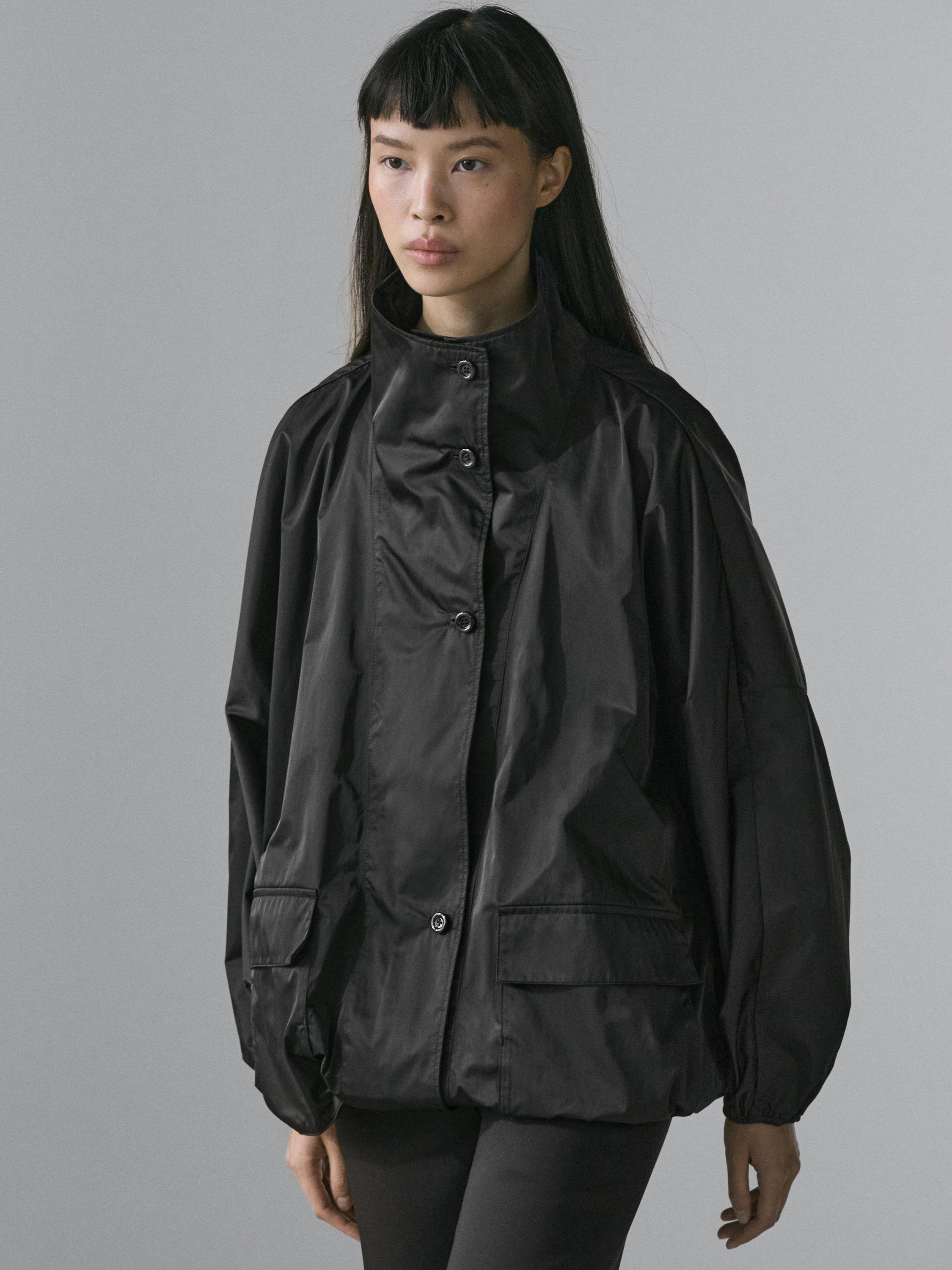 Комплект из черной куртки с высоким воротником, передней планкой на пуговицах и передними карманами с клапанами.