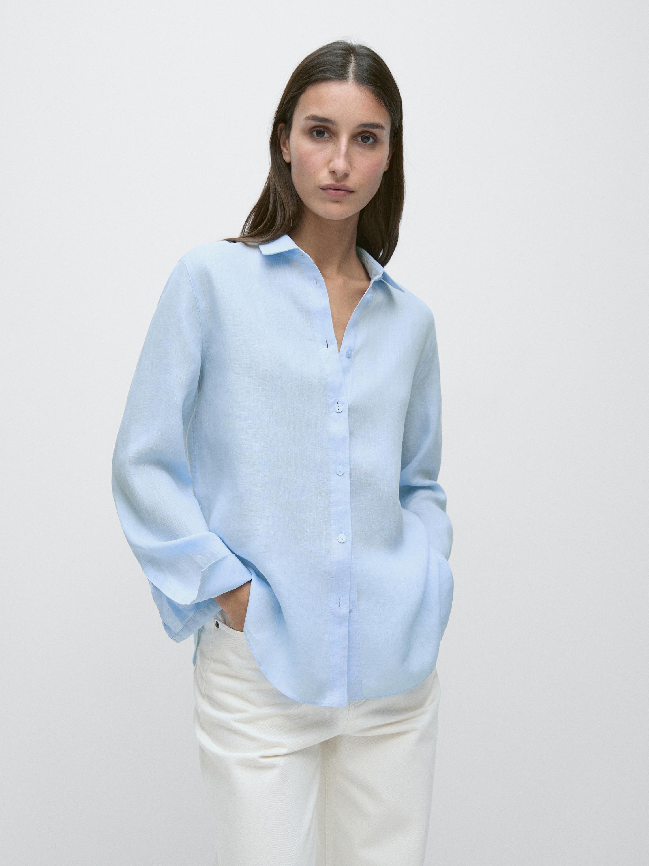 Set aus hellblauem, fließendem Hemd mit Knöpfen und seitlichen Taschen, kombiniert mit einer weißen Hose.