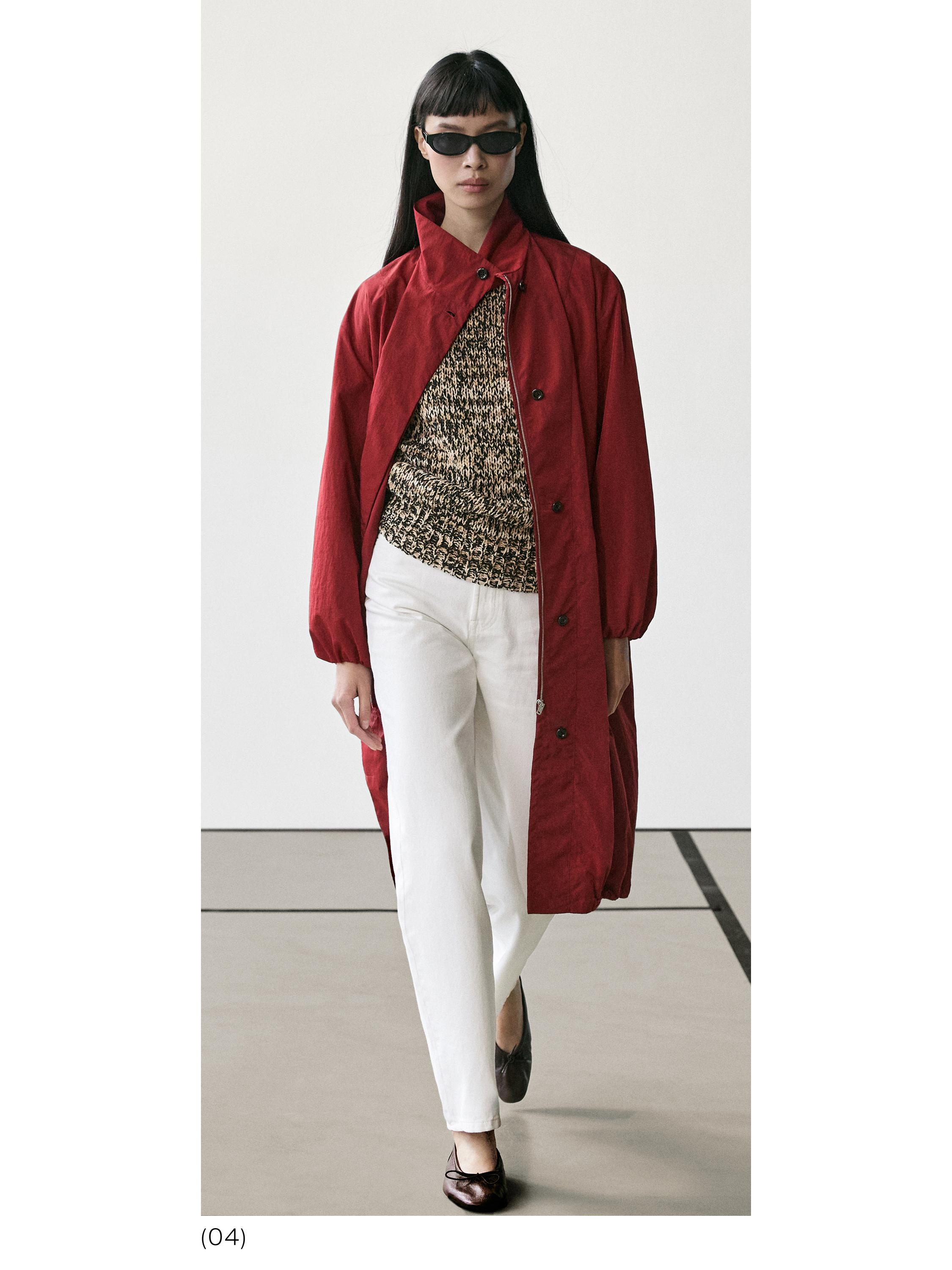 Komplet me pallto të kuqe me kopsa, top me print në të zezë dhe beixh, pantallona të bardha dhe këpucë të zeza.