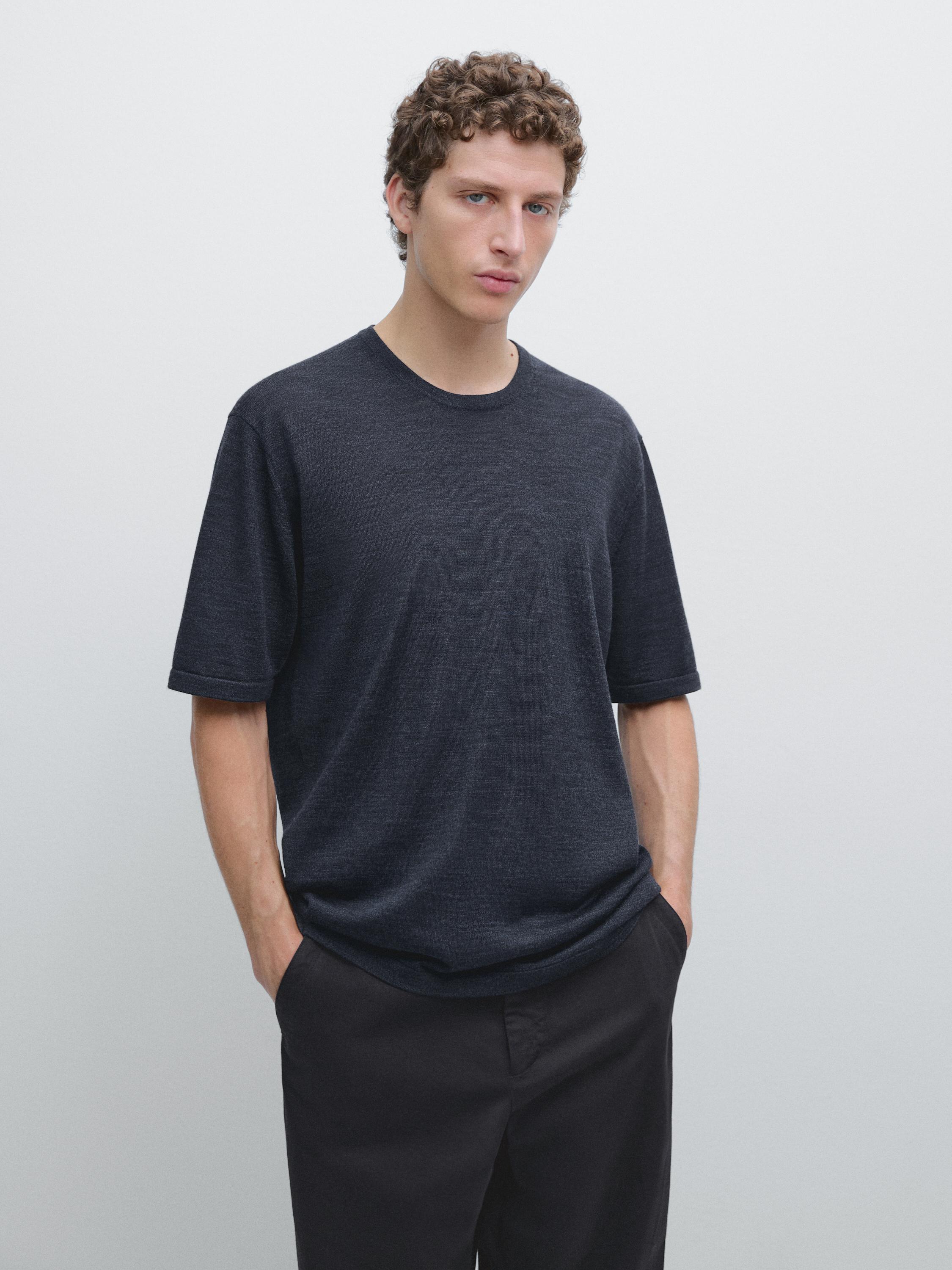 Completo di t-shirt blu scuro a maniche corte e pantaloni neri. Tasche laterali visibili sui pantaloni.