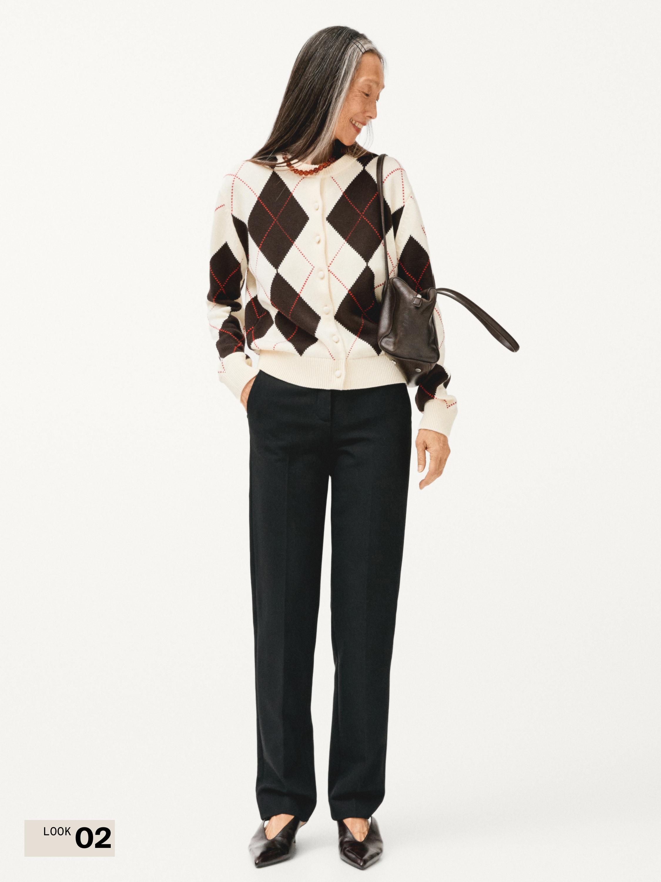 버튼이 달린 갈색 및 흰색 마름모 패턴 가디건 세트와 검은색 스트레이트 팬츠.