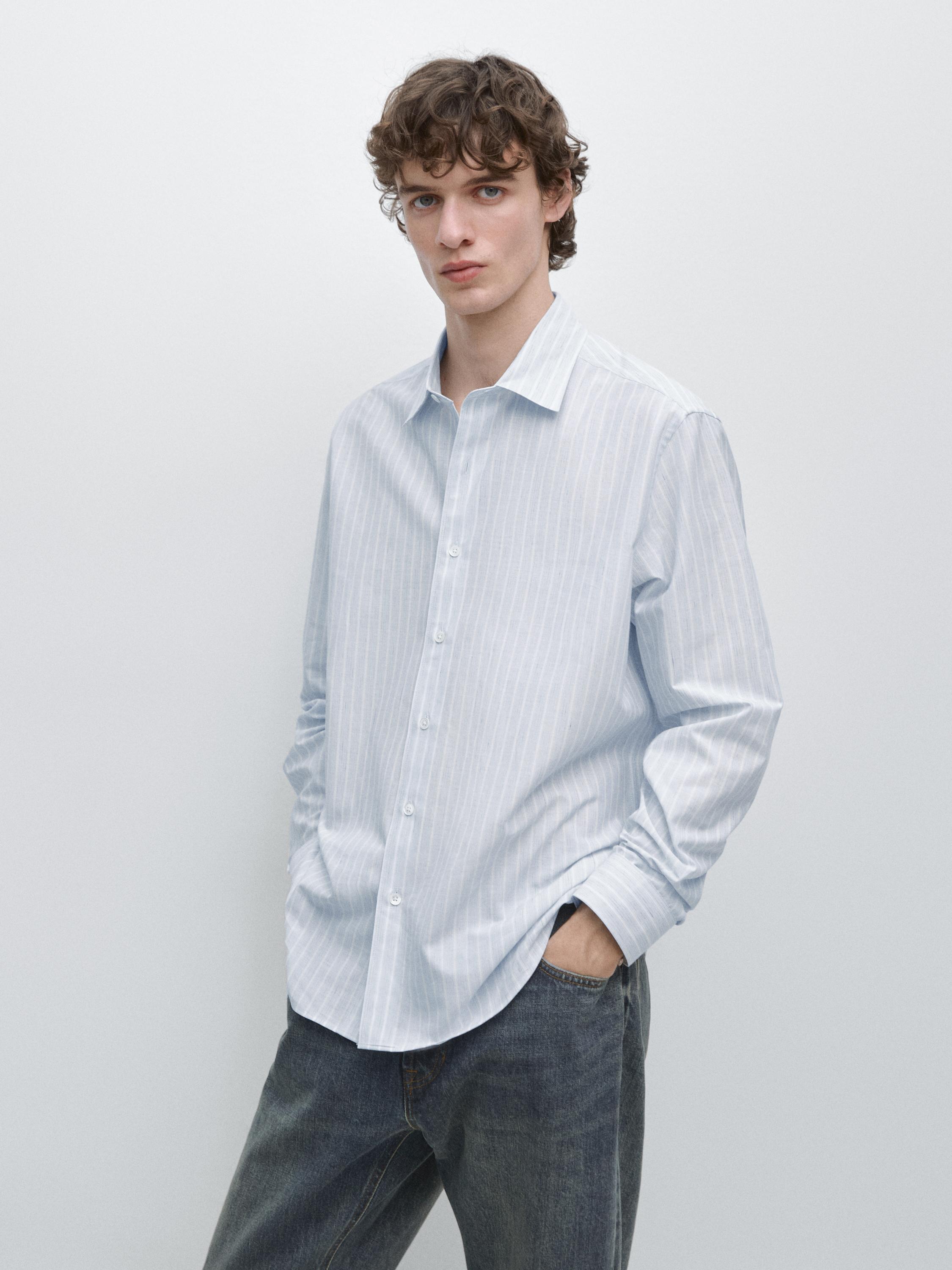 Halbaufnahme eines hellblauen Hemdes mit vertikalen Streifen, langen Ärmeln und Knopfleiste vorne.