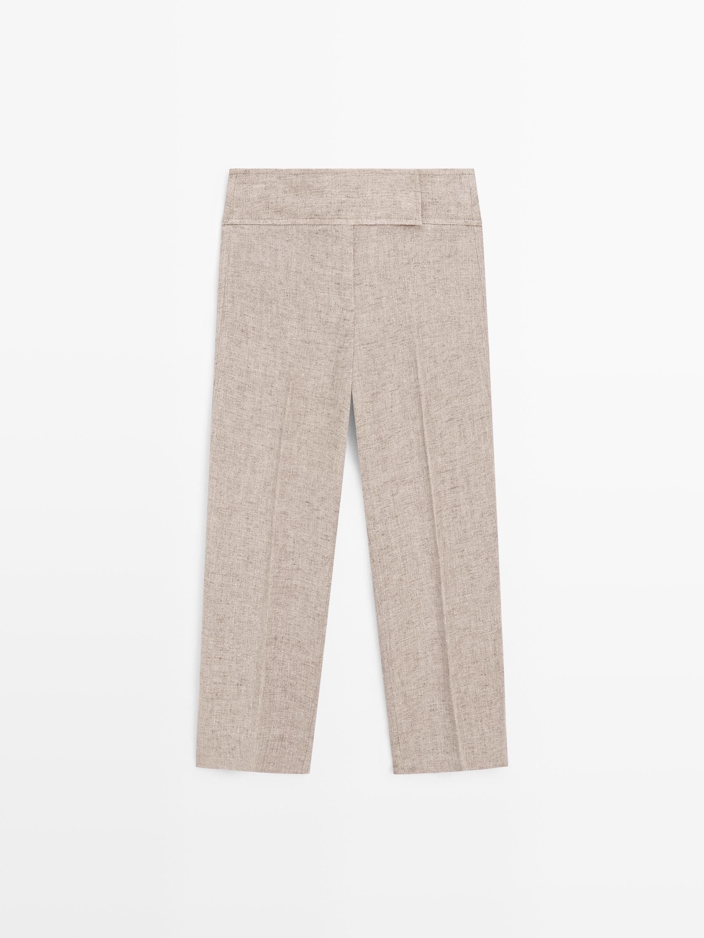 Vista posterior de calças bege com pregas frontais e cós largo.