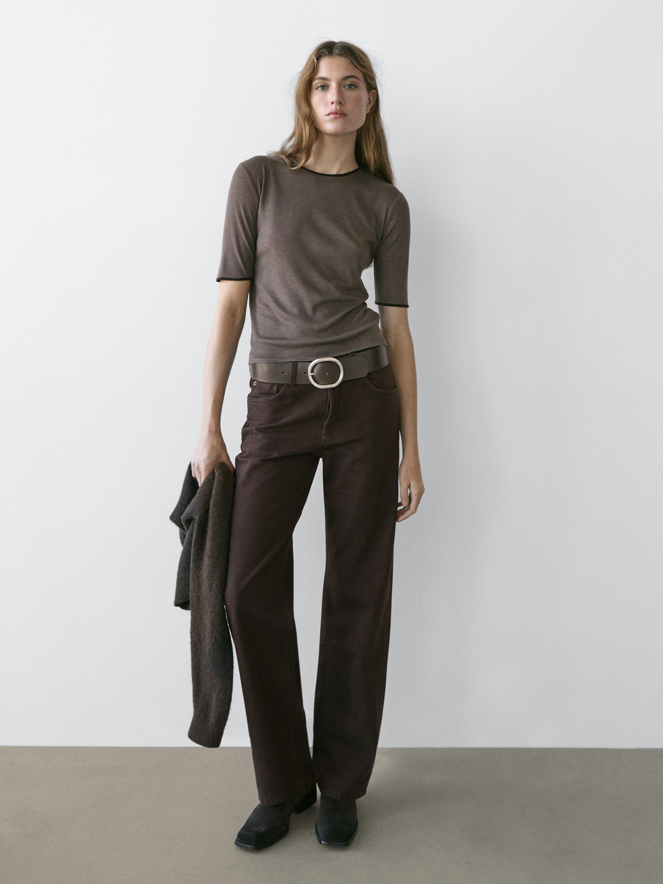 Pruun lühikeste varrukatega t-särk ja laia säärega šokolaadivärvi teksad suure vööga.