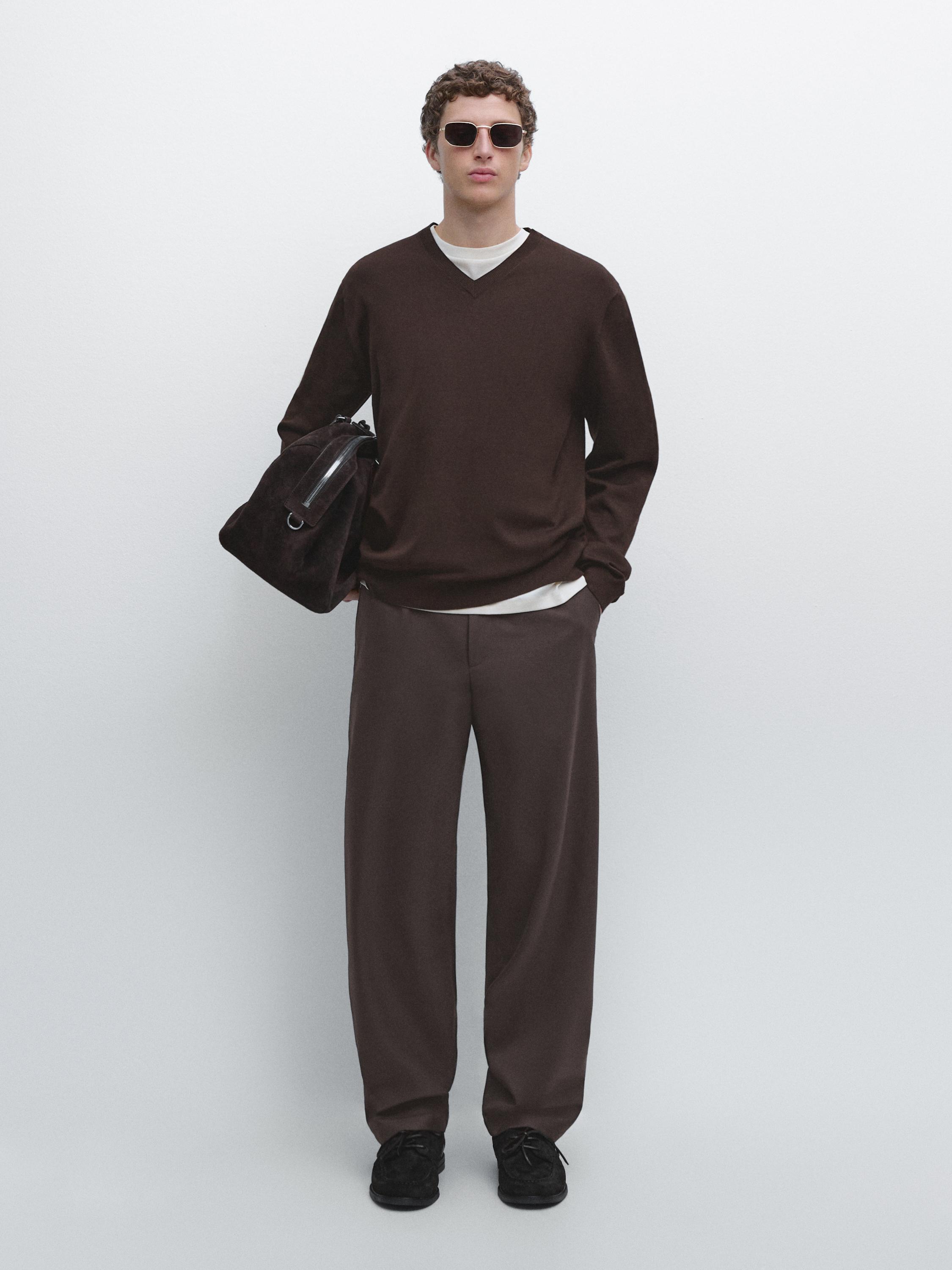 Completo di maglione marrone con scollo a V e pantaloni marroni dritti.