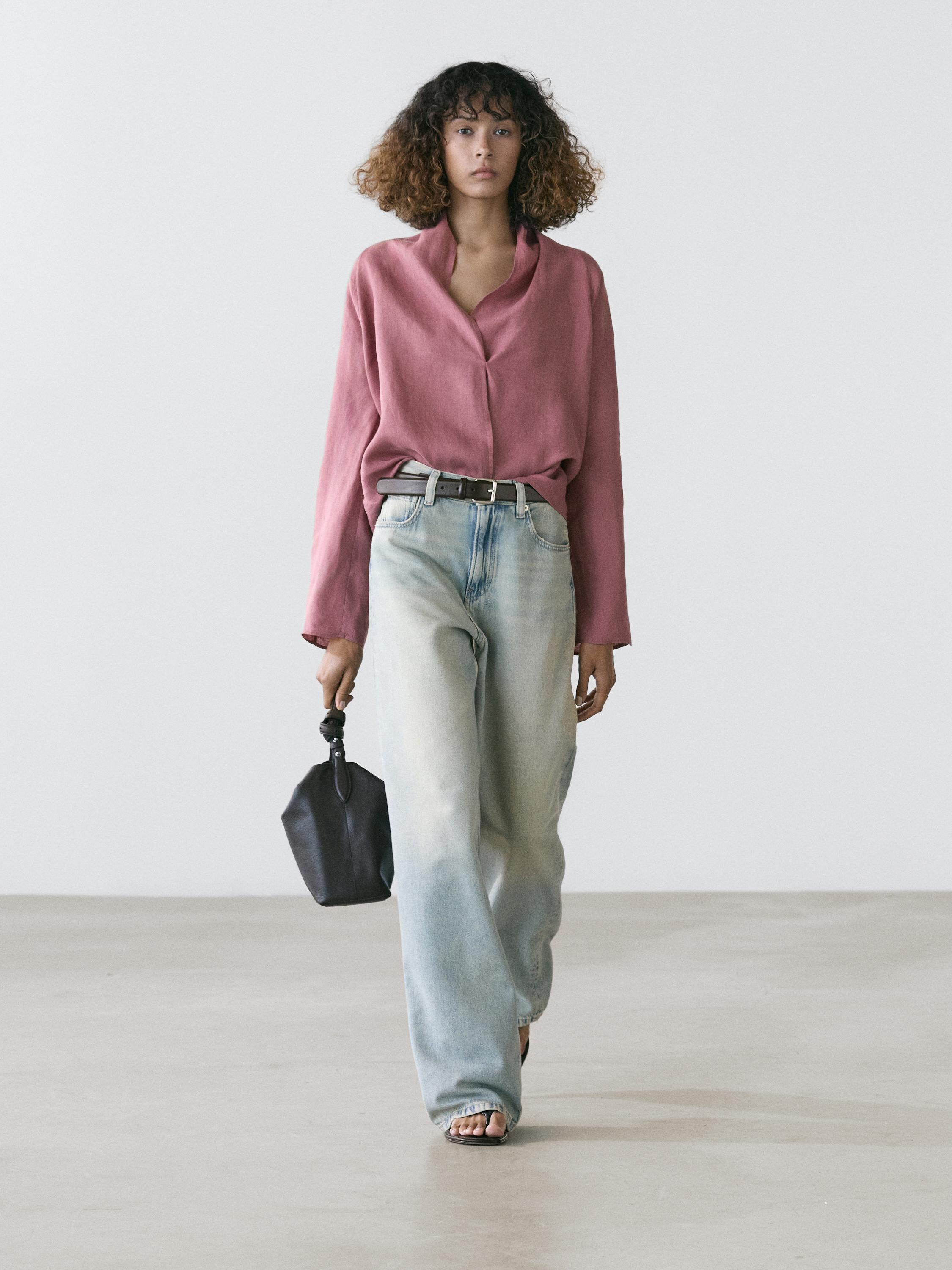 Conxunto de blusa rosa cruzada de manga longa e vaqueiros anchos azul claro con petos dianteiros.