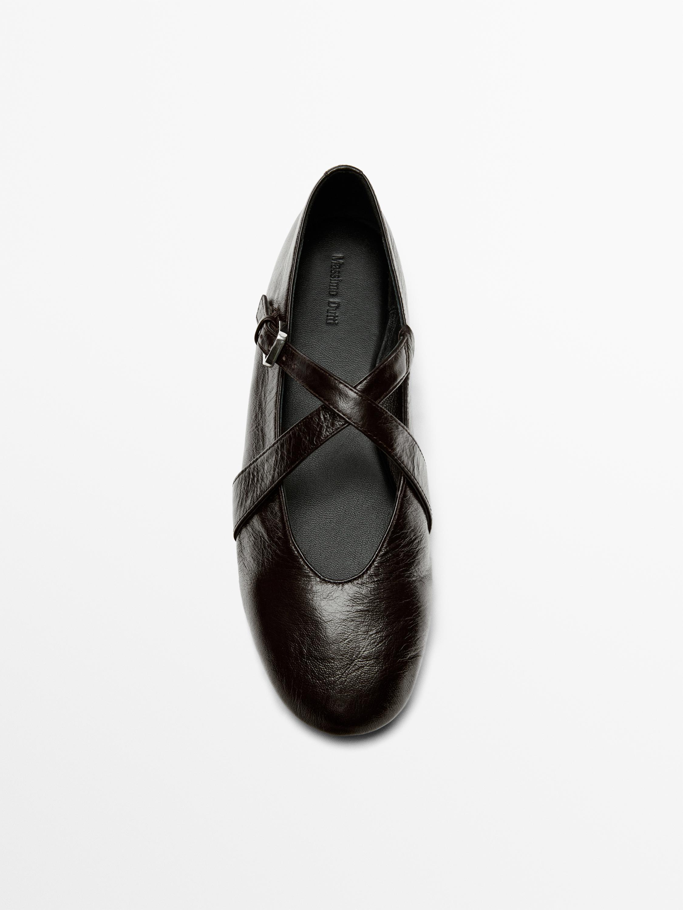 มุมมองด้านบนของรองเท้าบัลเลต์สีน้ำตาลแบบมีสายไขว้และหัวเข็มขัด มองเห็นข้อความด้านใน: "Massimo Dutti"