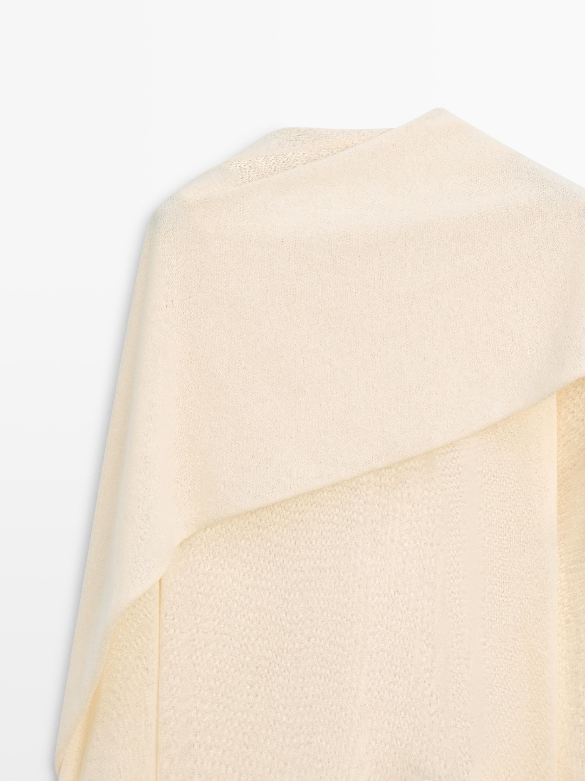 Vainilla koloreko soineko baten goiko aldearen xehetasuna, lepoan diseinu asimetrikoa duena.