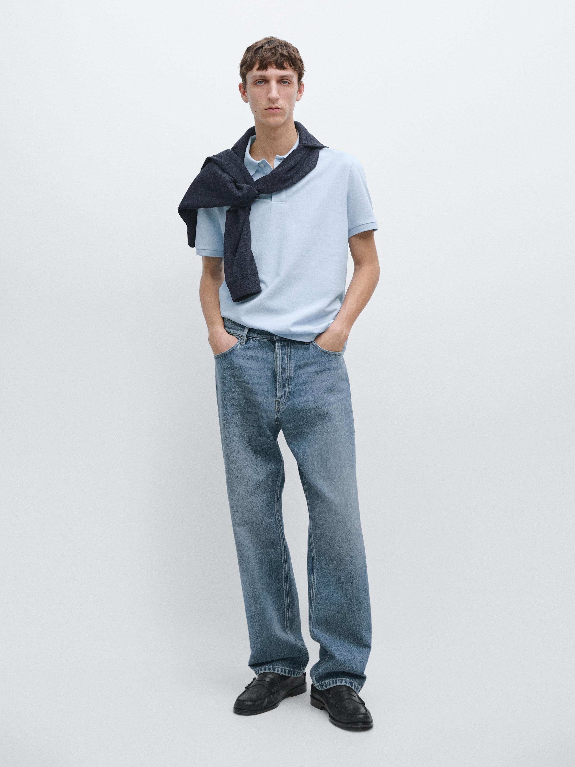 Light blue short-sleeved polo shirt and straight blue jeans set. Dark sweater tied around the neck.