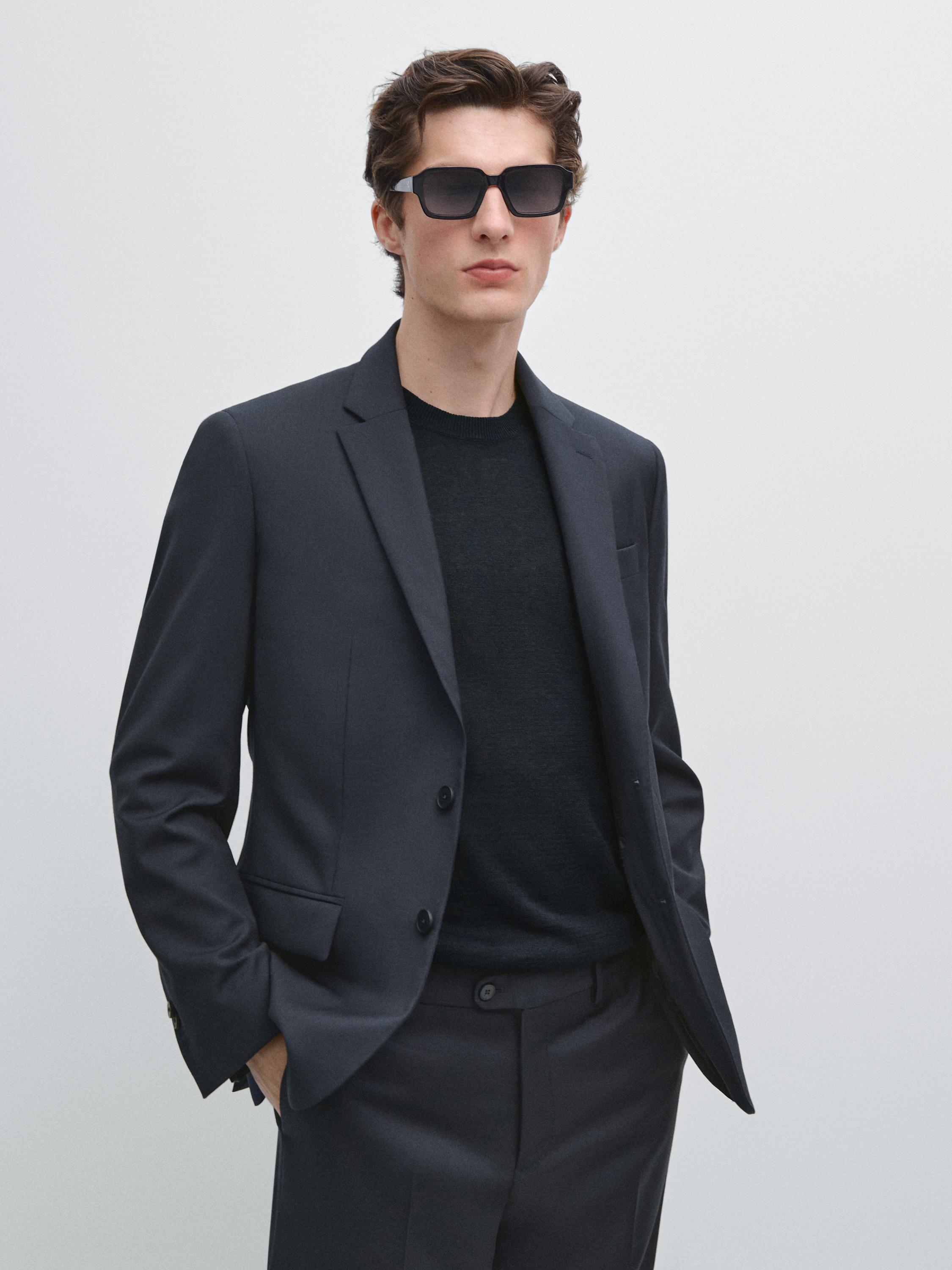 Marineblauwe blazer set met knopen en steekzakken, bijpassende broek en zwart T-shirt.