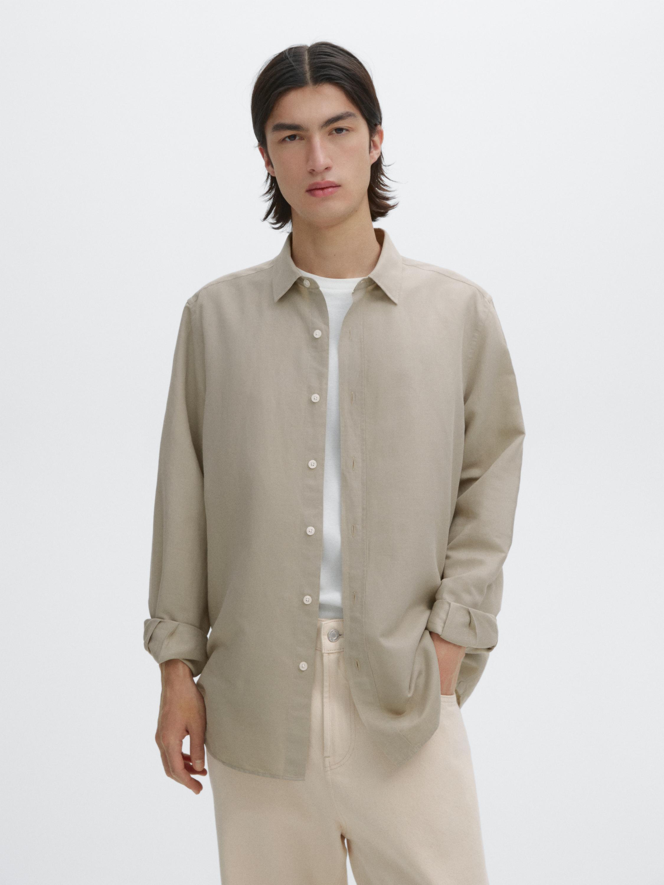 طقم مكون من قميص بيج بأزرار وياقة كلاسيكية وبنطلون فاتح اللون.