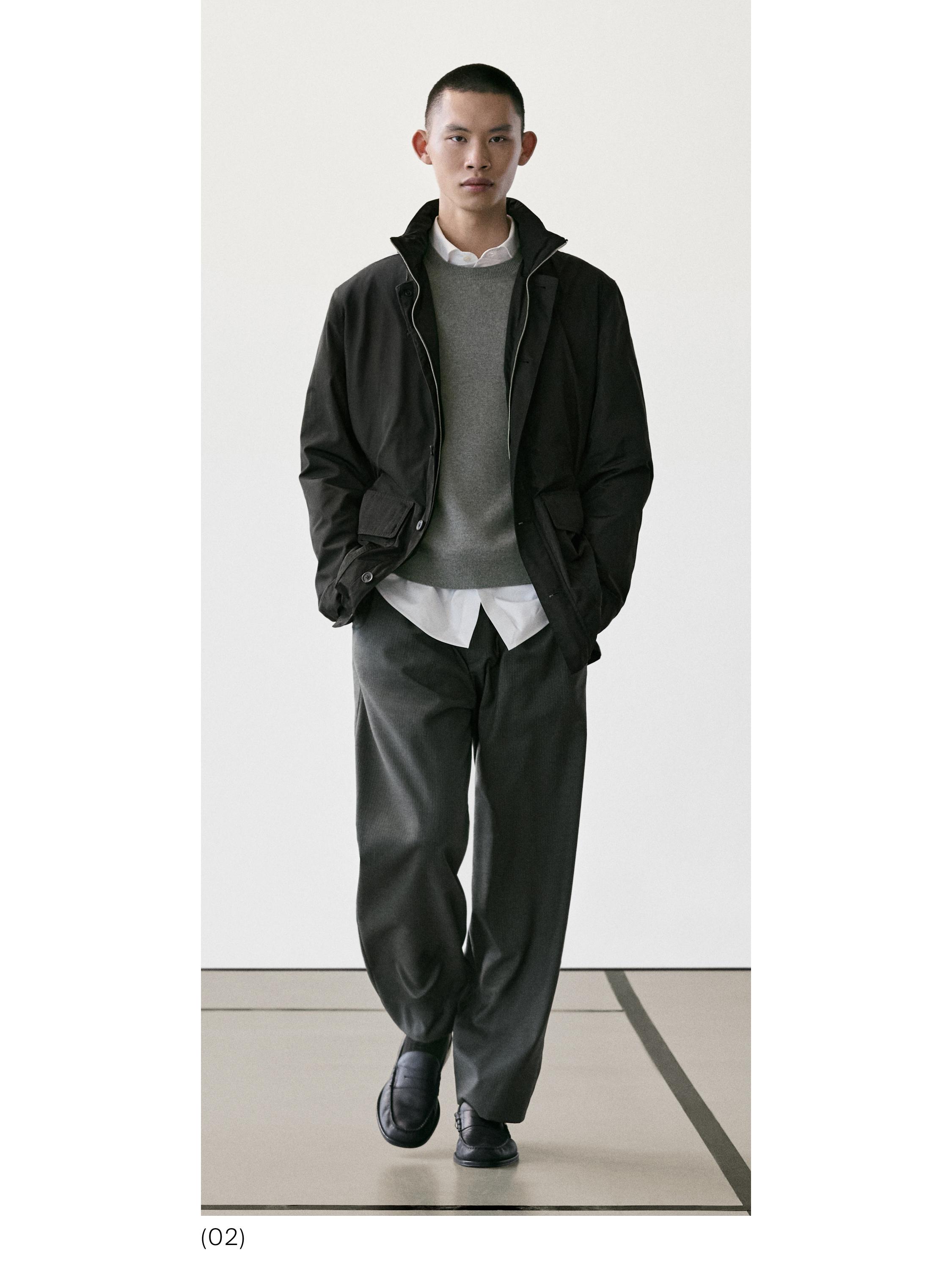 Conxunto de chaqueta negra con petos, xersei gris, camisa branca, pantalóns anchos grises e zapatos negros.