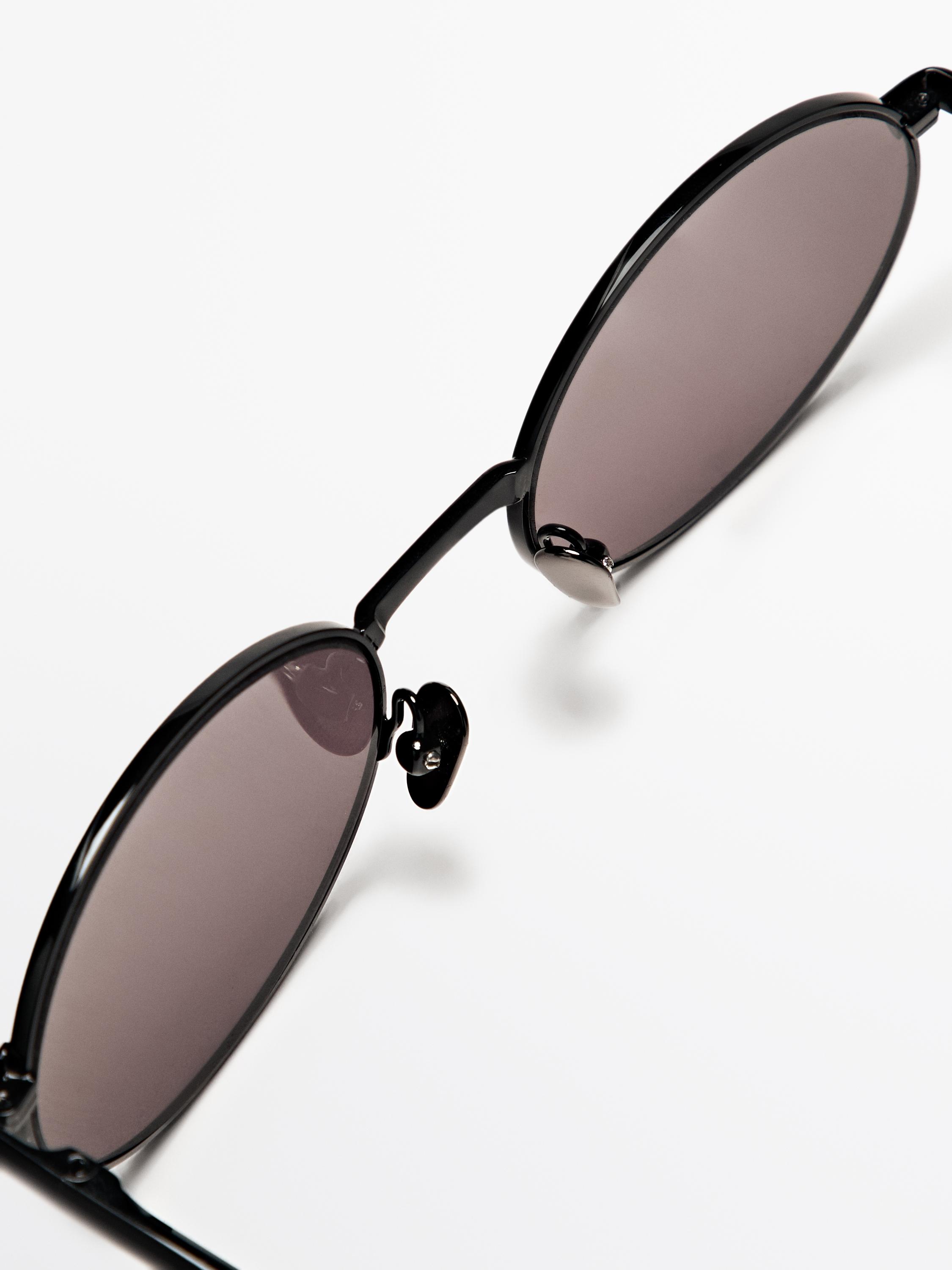 Close-up of black sunglasses with a round frame and narrow bridge.