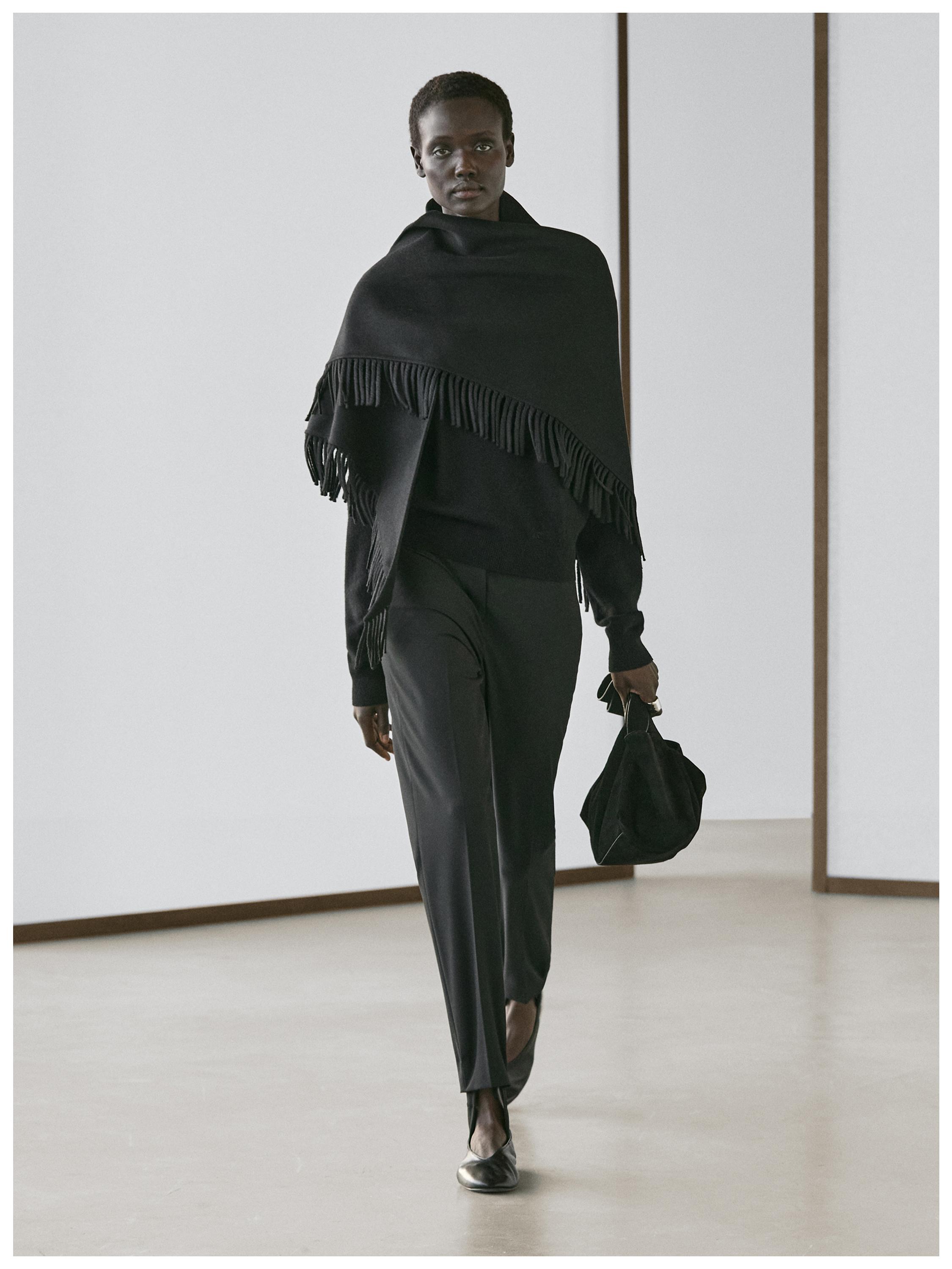 Black fringe scarf set, black sweater, and black straight-leg pants.