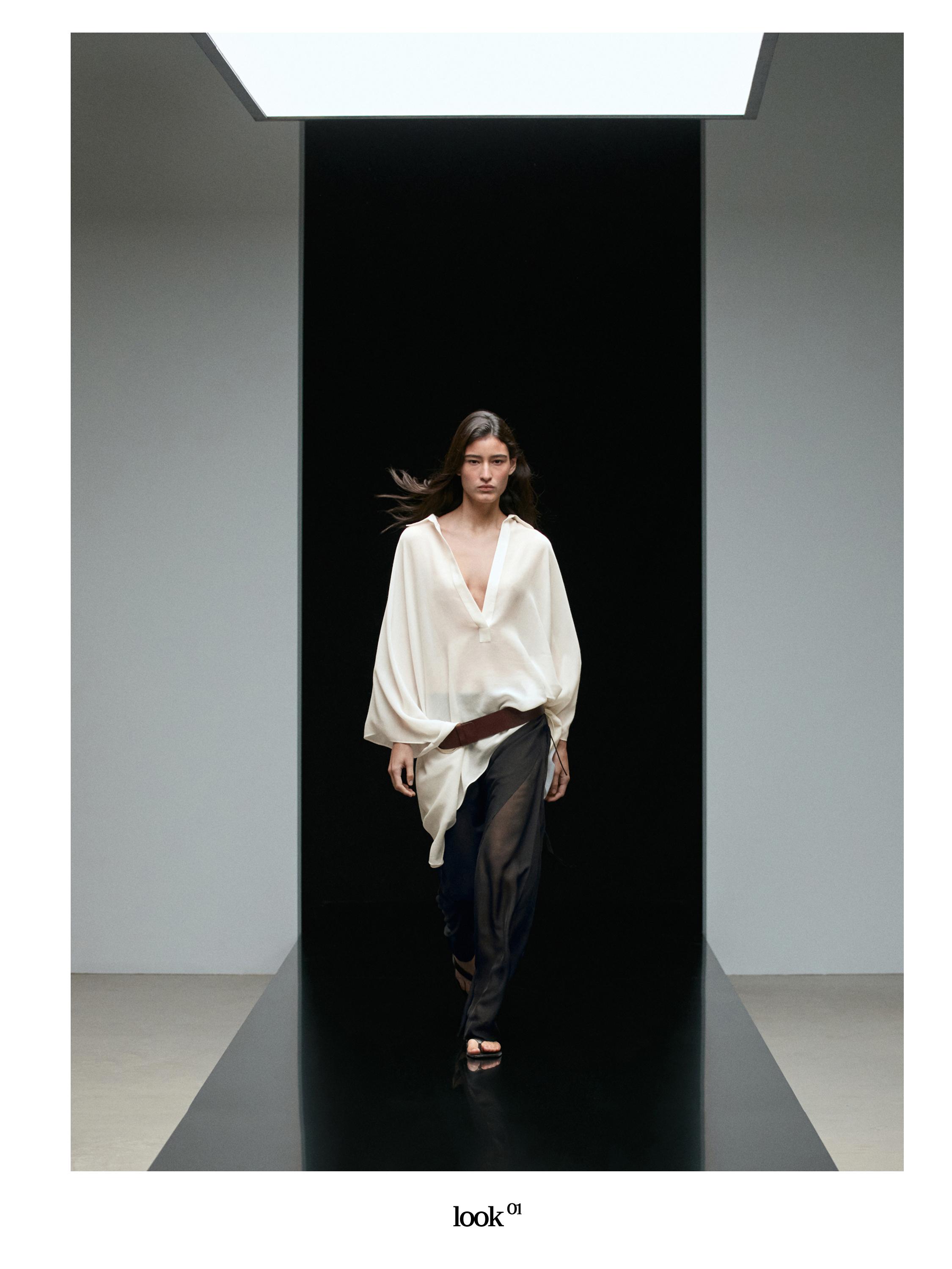 Conjunto de blusa blanca de escote profundo y falda pantalón negra larga translúcida.